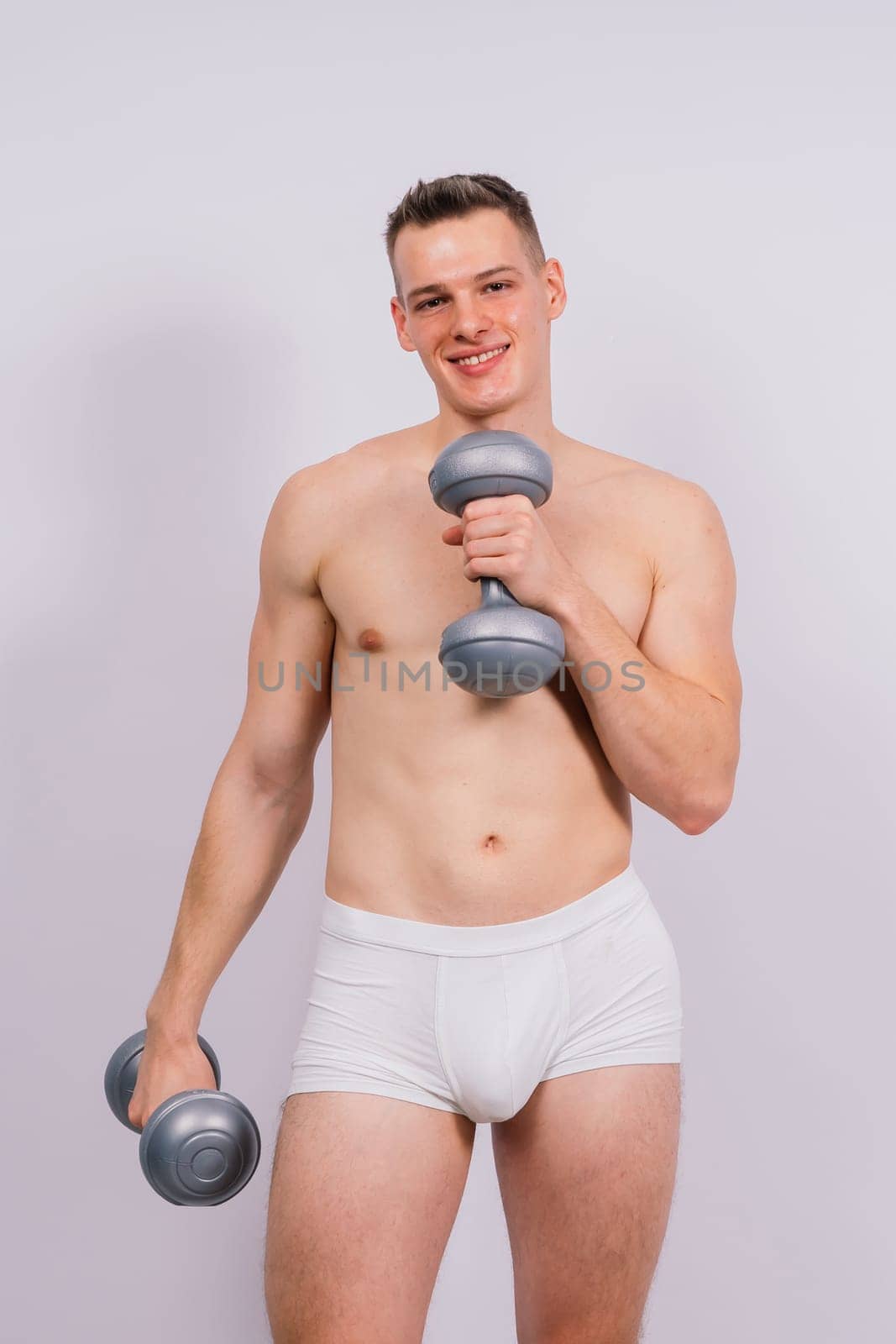 Shirtless bodybuilder holding a dumbell and showing his muscular arms.