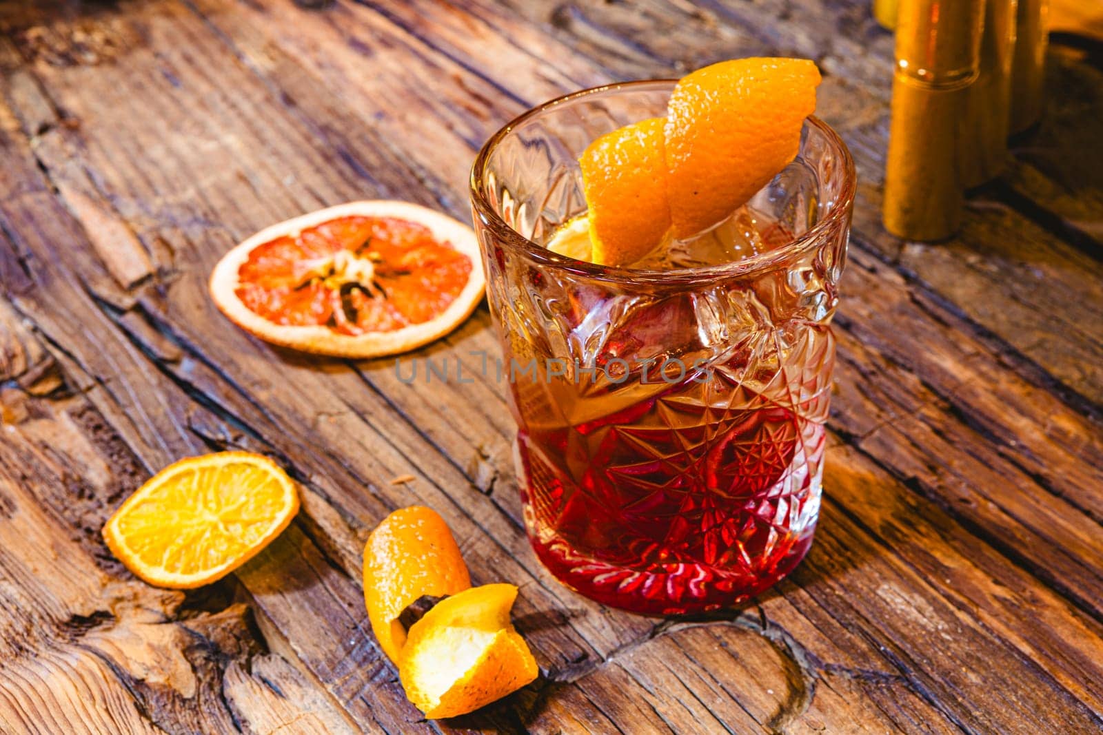 Delicious old fashion cocktail in the etched glass with ice and orange slices, dark wooden background. Shallow dof.