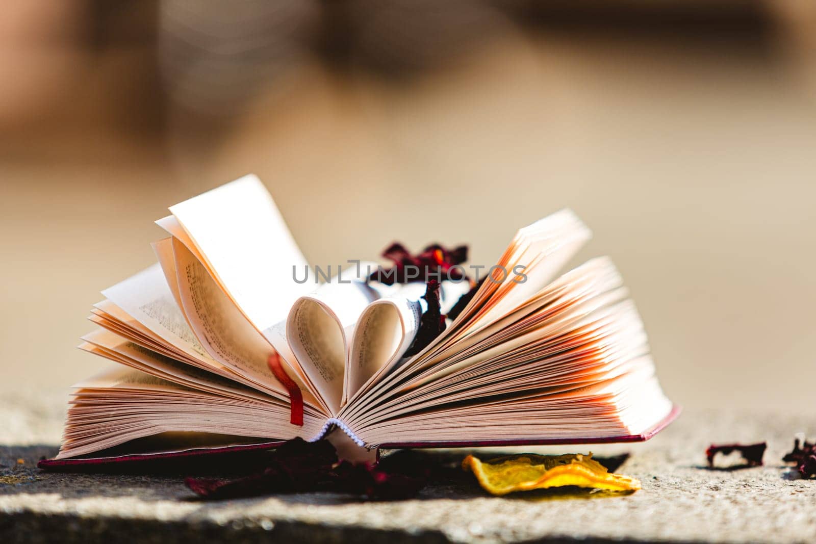 Stack of books in the colored cover lay on the table. Open book with curled leaves in the shape of a heart. Library, education. Love of books, reading. Empty space for Your text on the left. Shallow dof