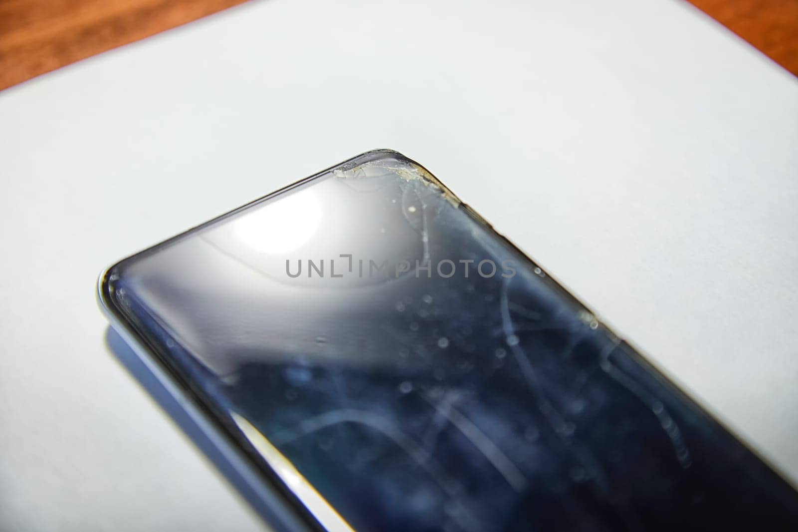 Close-Up View of a Cracked Smartphone Screen Against White Background. the detailed texture of a shattered smartphone screen, emphasizing extensive damage to the device