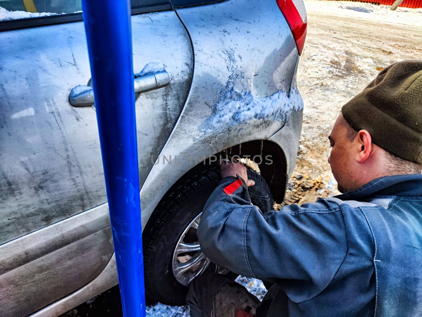 Ishim, Russia - November 27, 2023: man makes tire of car wheel before cold snow season. Experienced mechanic changes wheel of car. The driver prepares a classic car for driving in the snow in winter