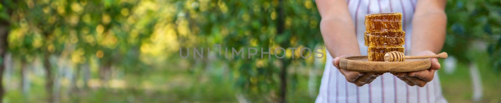 A woman holds honey in the garden. Selective focus. Nature.