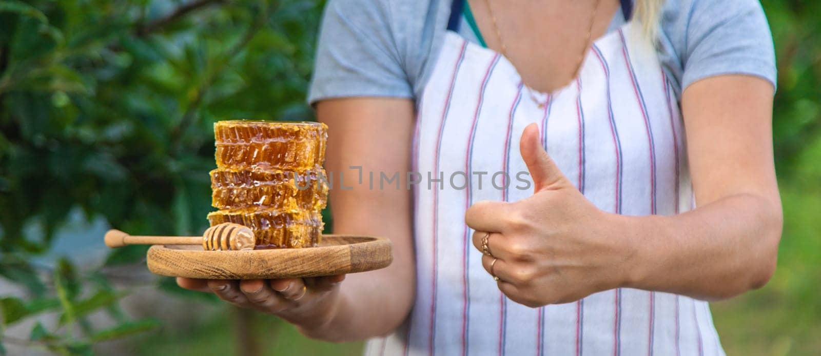 A woman holds honey in the garden. Selective focus. Nature.