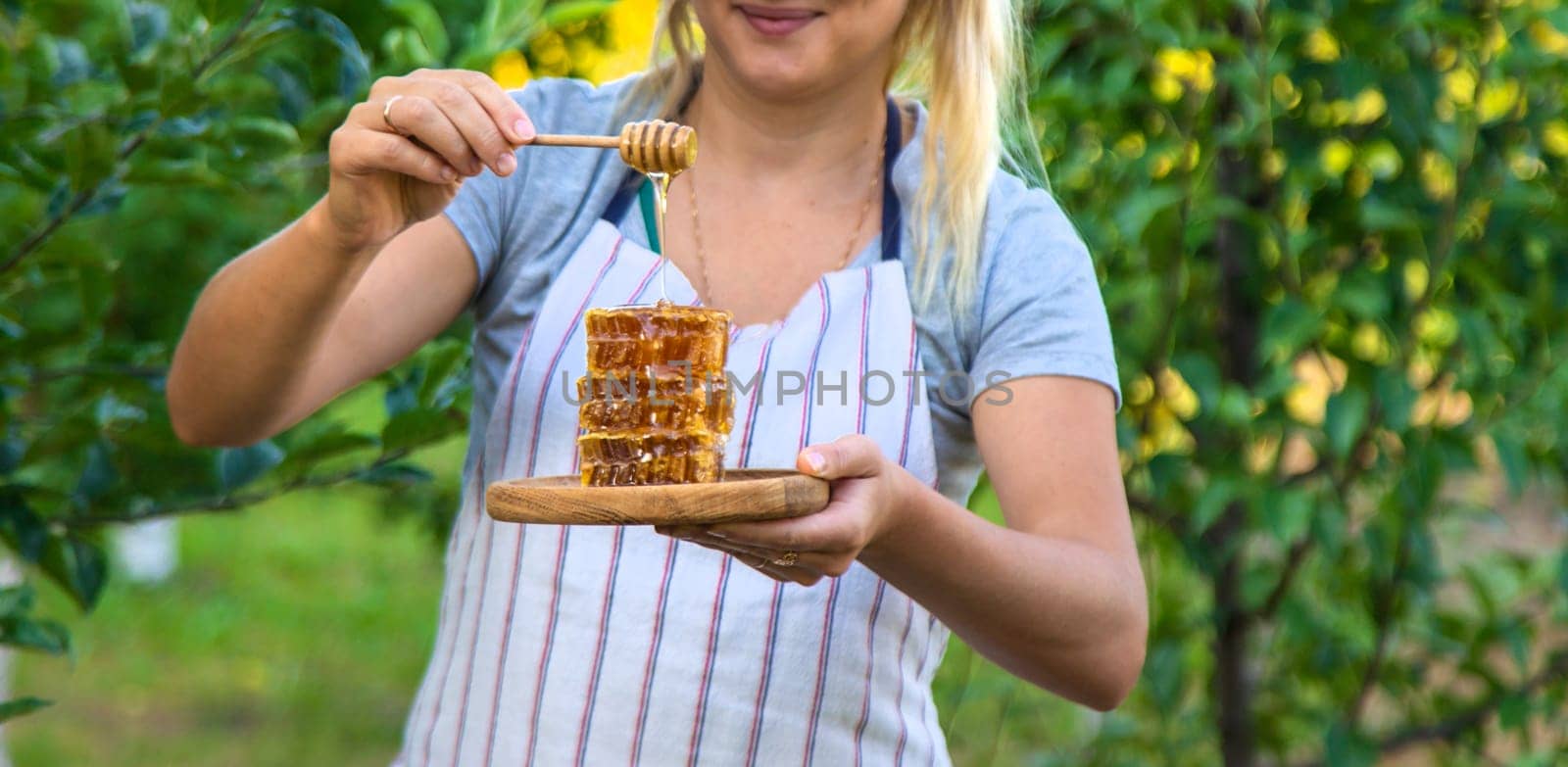 A woman holds honey in the garden. Selective focus. Nature.