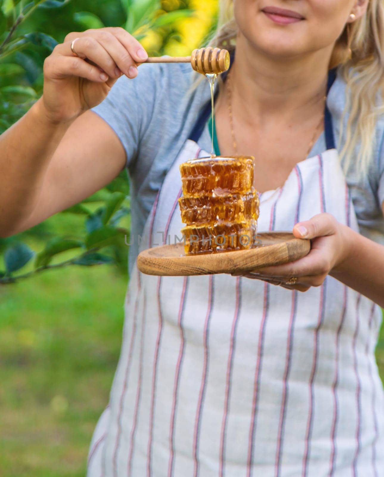 A woman holds honey in the garden. Selective focus. Nature.