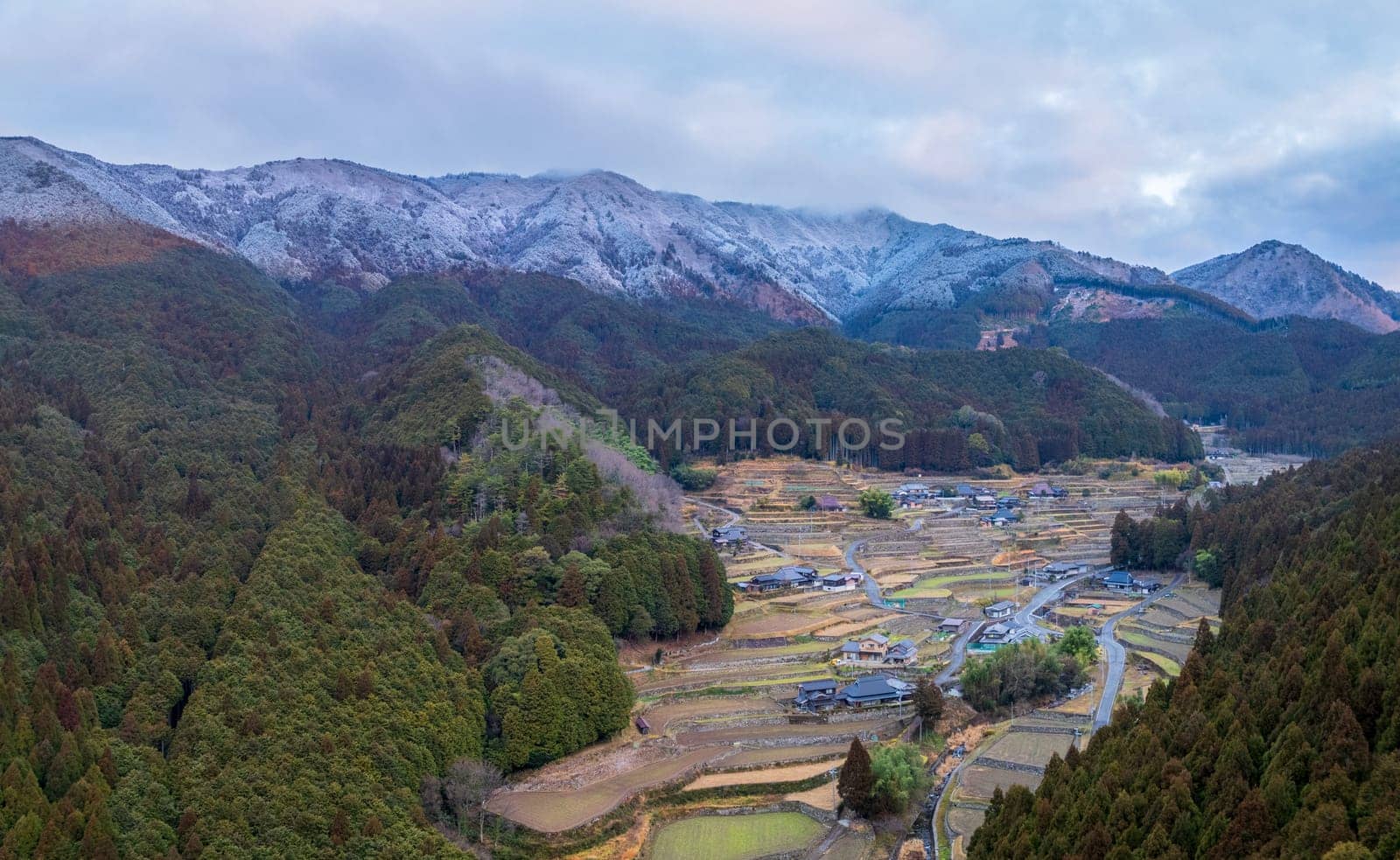 Aerial view of terraced rice fields in small village by snowy mountains. High quality photo
