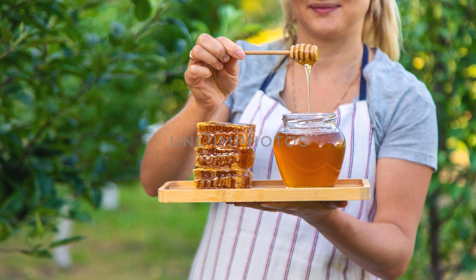 A woman holds honey in the garden. Selective focus. Nature.