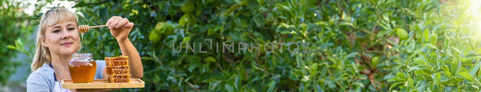 A woman holds honey in the garden. Selective focus. Nature.