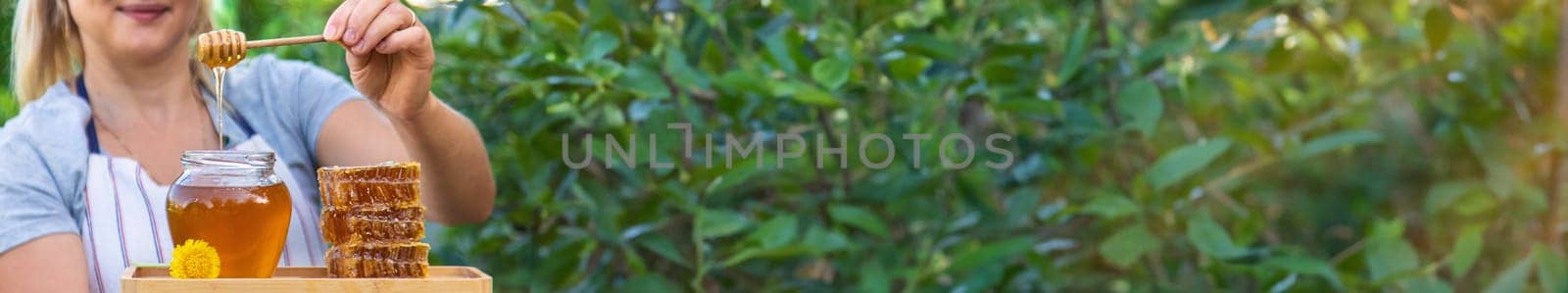 A woman holds honey in the garden. Selective focus. Nature.