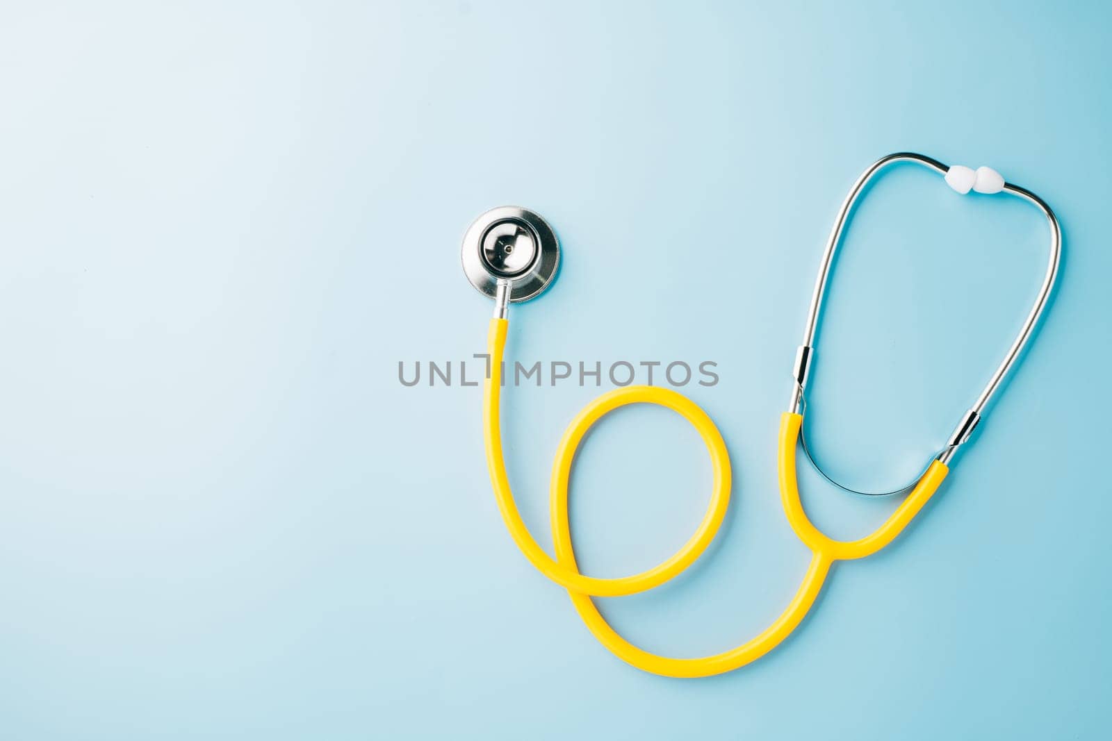 Topv iew yellow medical stethoscope isolated on blue background with copy space for you text, Doctor equipment, healthcare and medical, Doctor Day and World cancer day Concept