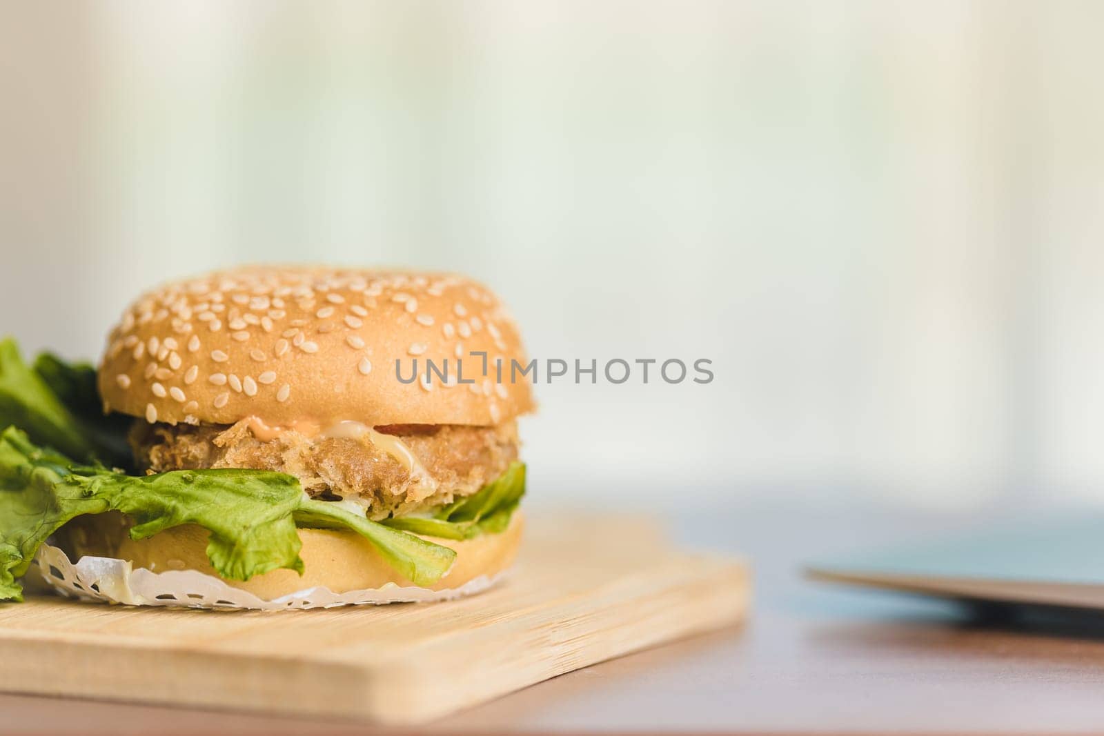 A delicious hamburger meal with cheese, lettuce, tomato, and beef on the work table for eating fast food at work concept