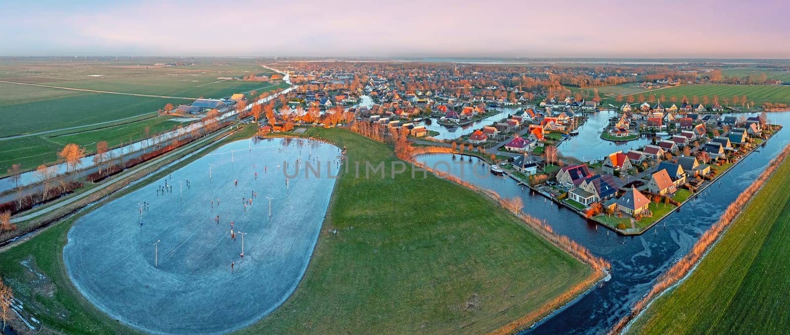 Aerial view on the traditional village Koudum with the ice rink in Friesland the Netherlands at sunset in winter