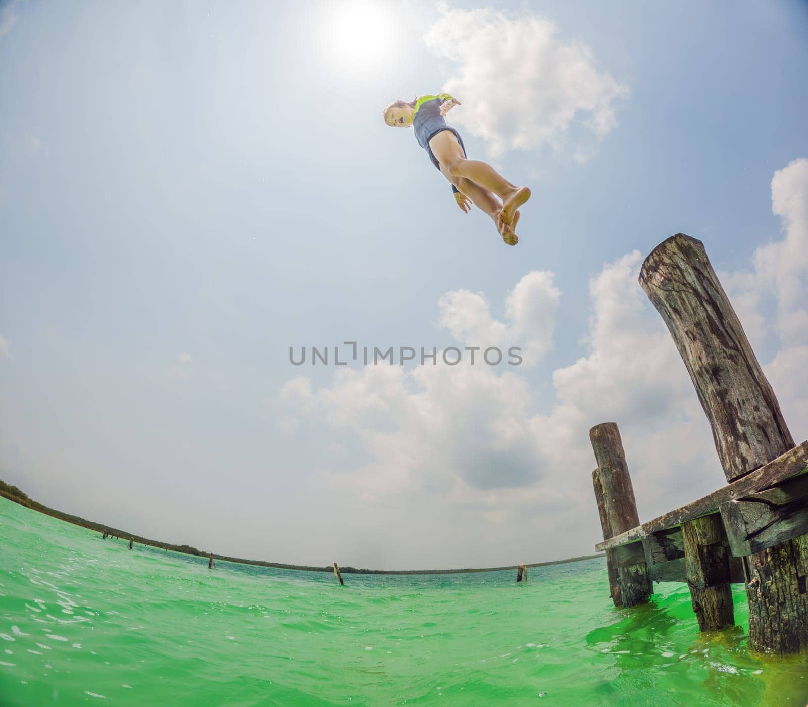 Joyful boy jumps into a turquoise lake in Mexico.