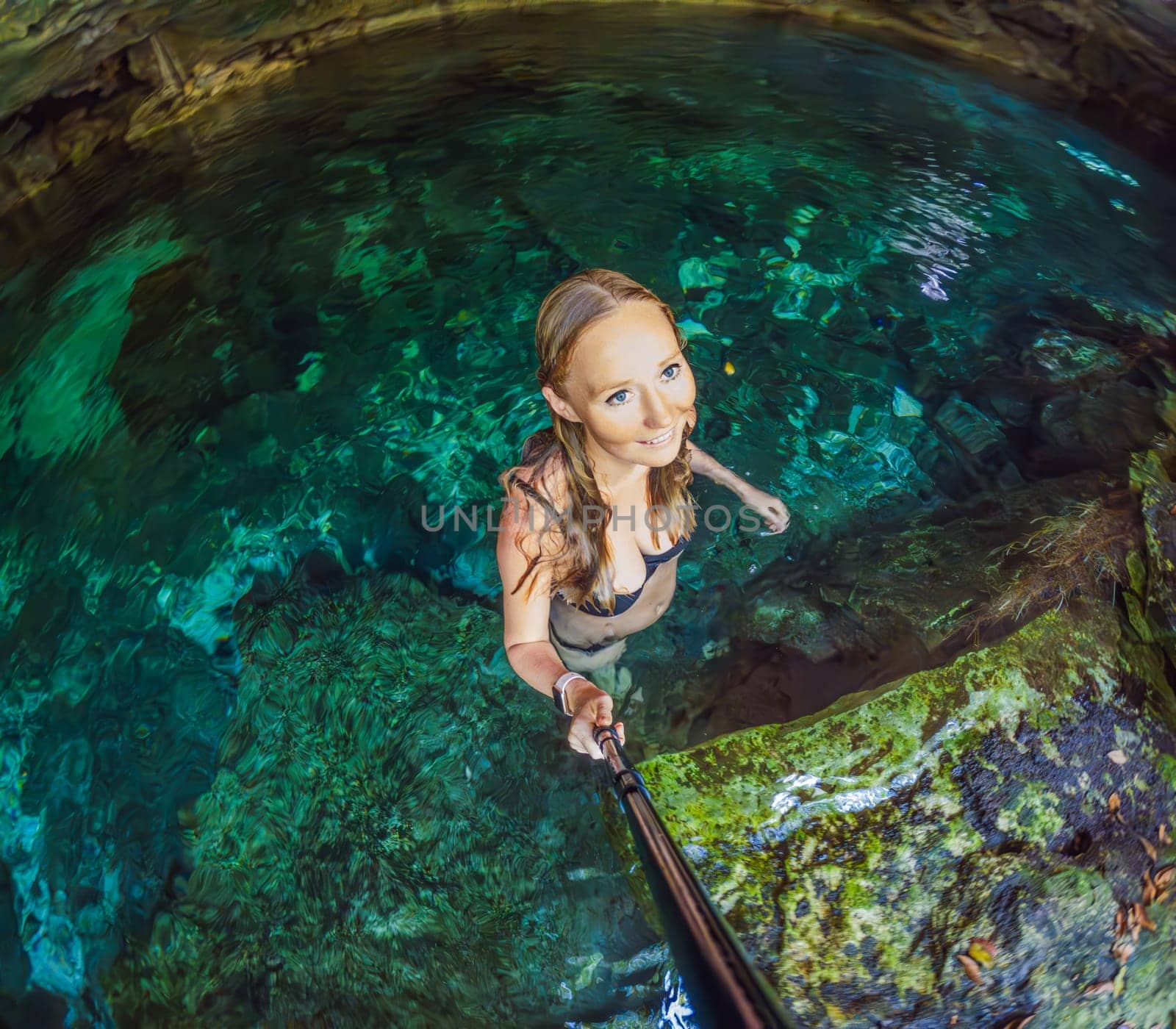 Woman immersed in the enchanting beauty of a Mexican cenote, surrounded by crystal-clear waters and captivating natural formations by galitskaya