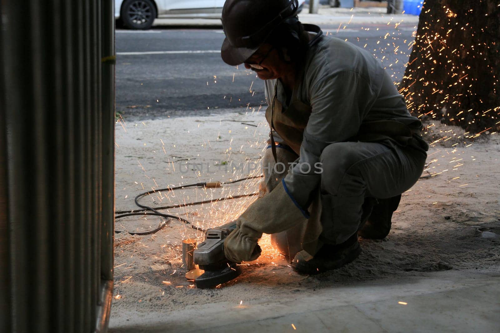 salvador, bahia, brazil - january 25, 2024: worker uses cutting disc to cut metal at a construction site in the city of Salvador.