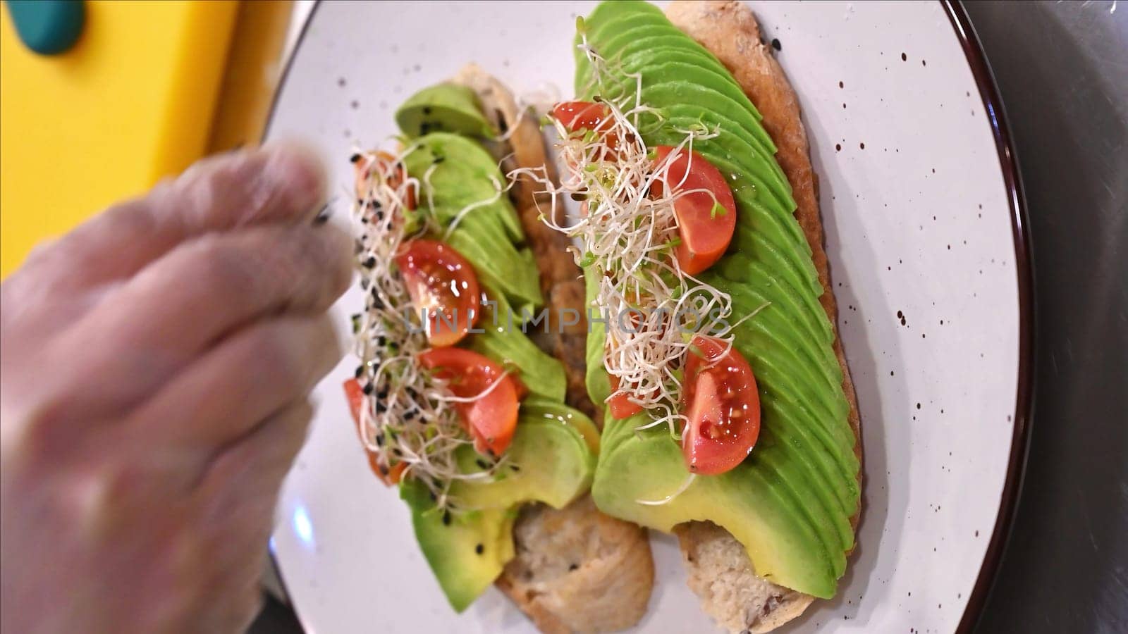 Avocado toast with small tomatoes on rye bread toast with soft cheese and sprouts. Healthy breakfast