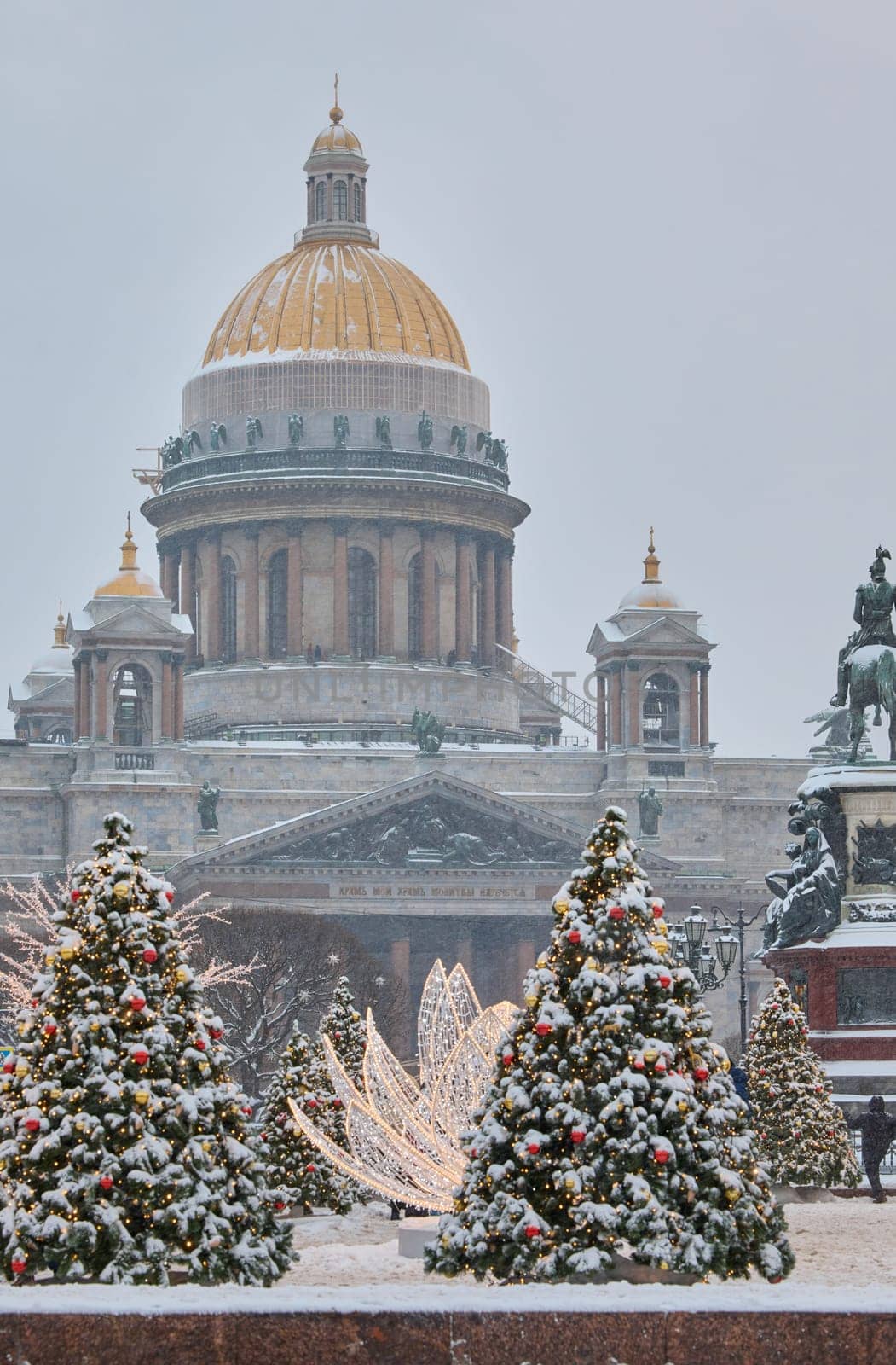 Russia, St Petersburg, St. Isaac's Cathedral and the monument to Emperor Nicholas II through lighting decorations during snowstorm, streets decorated for Christmas. High quality photo