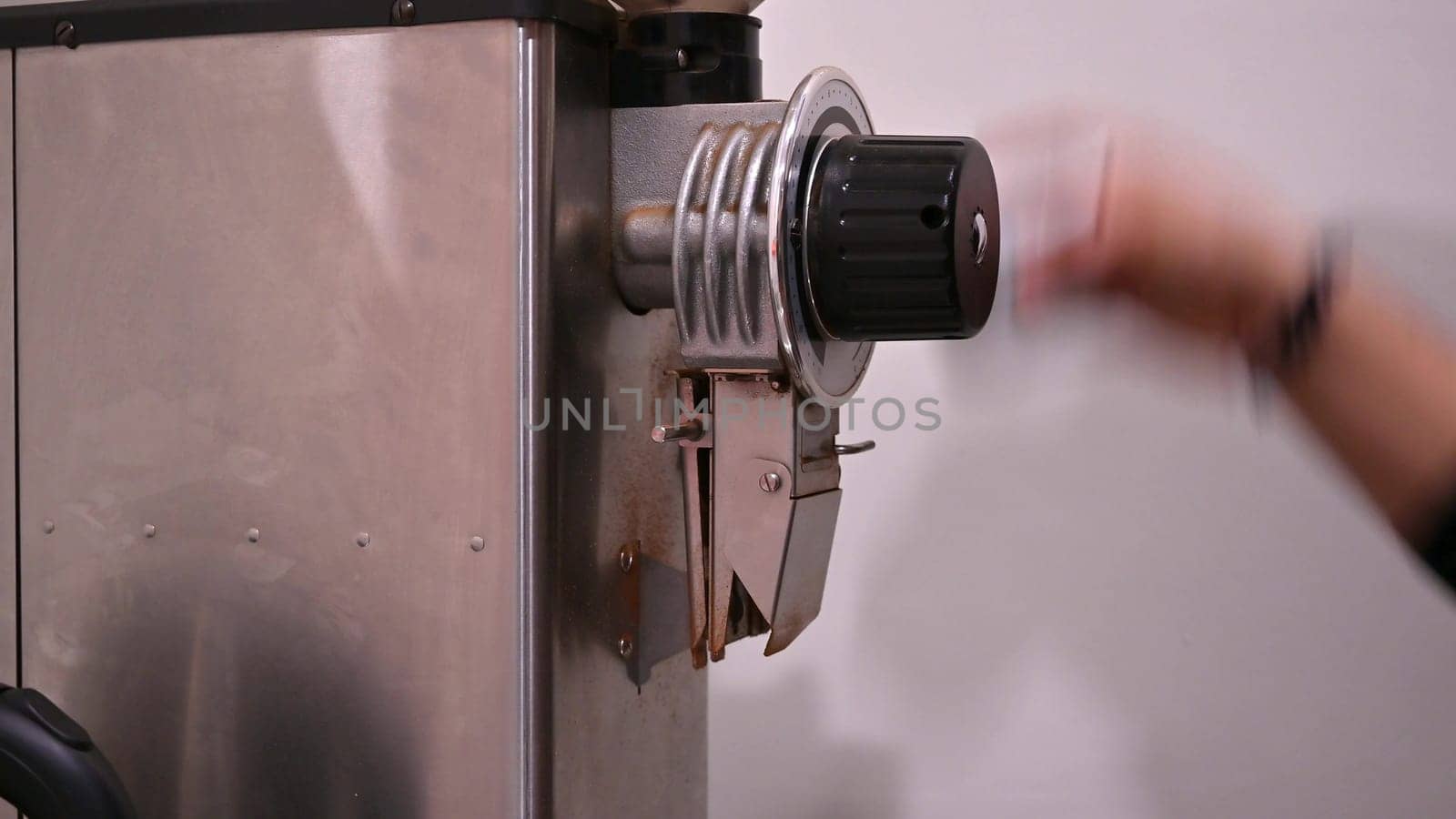 Hand of a barista extracting coffee from a coffee grinder by Peruphotoart