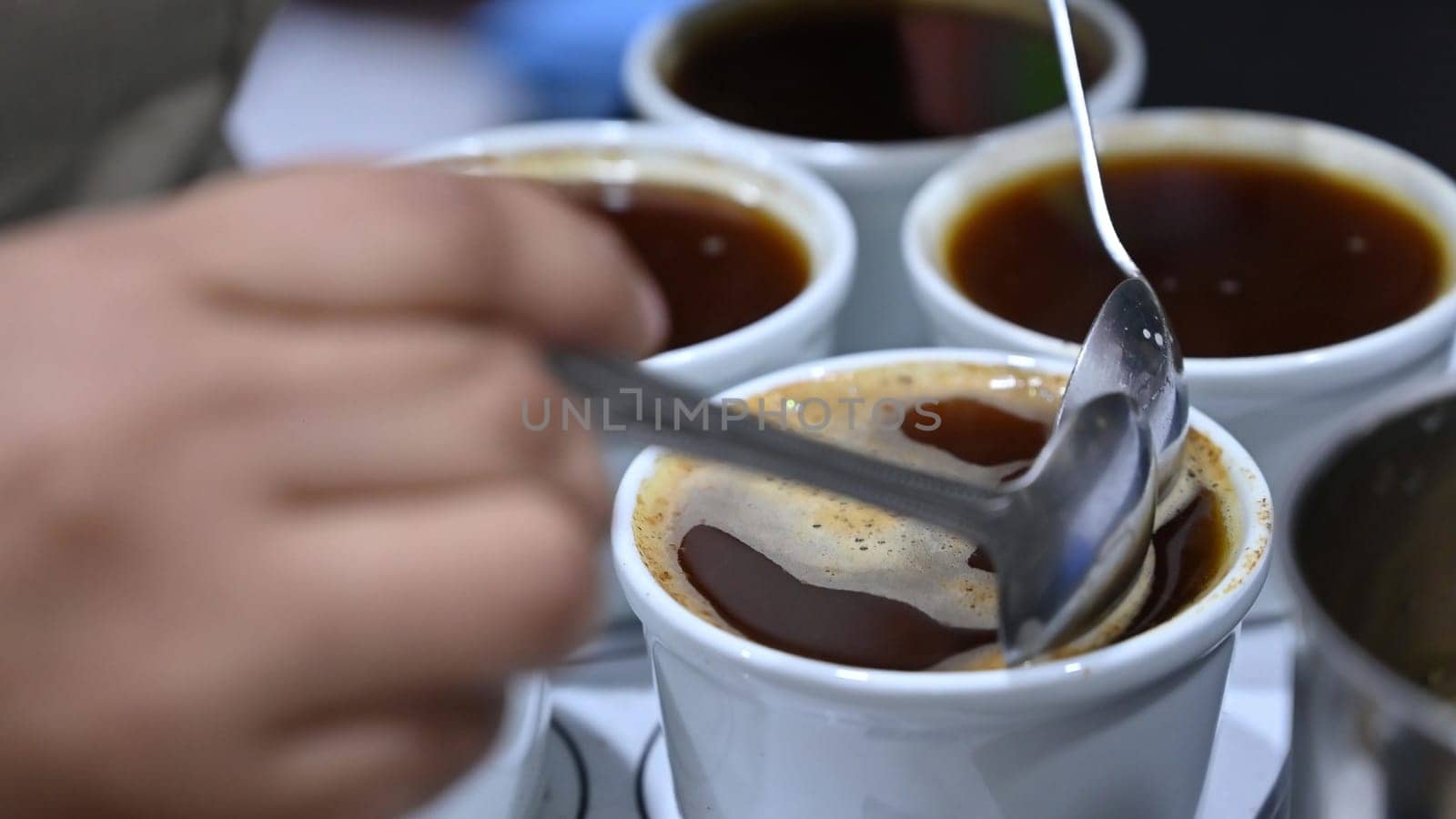 Professional barista tasting different types of coffee in cup tasters. Coffee degustation