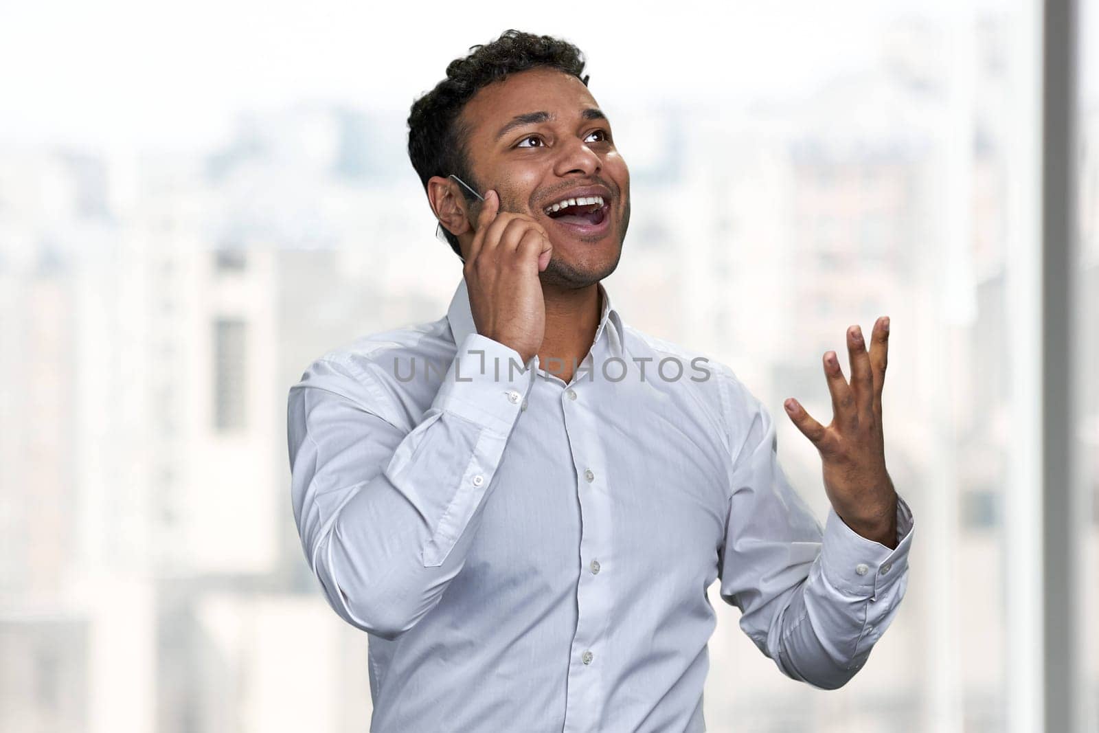 Happy emotional man wearing white shirt talking on futuristic phone. by super_picture