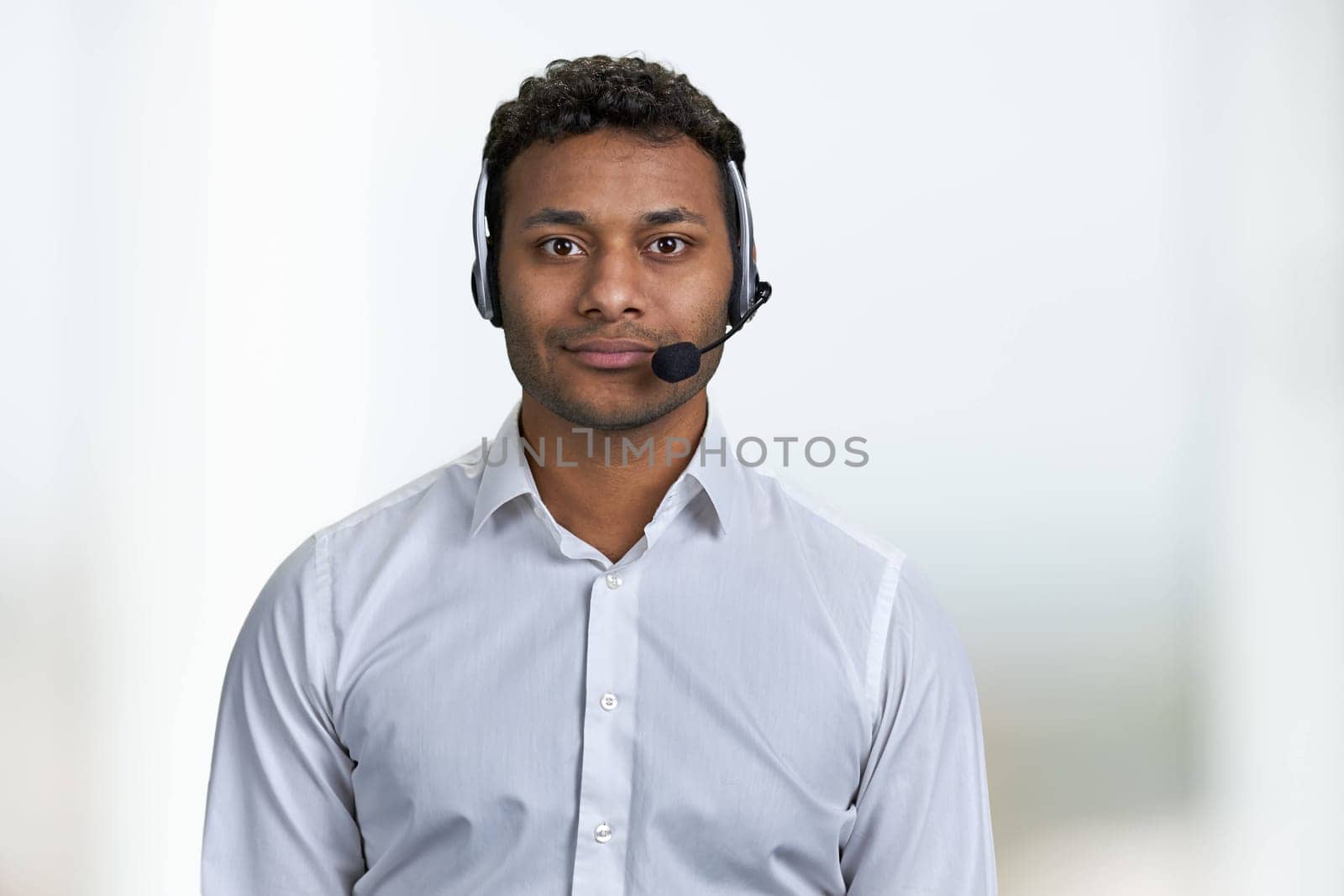 Handsome consultant of call center in headset looking at camera. Portrait of call center agent on blurred background.