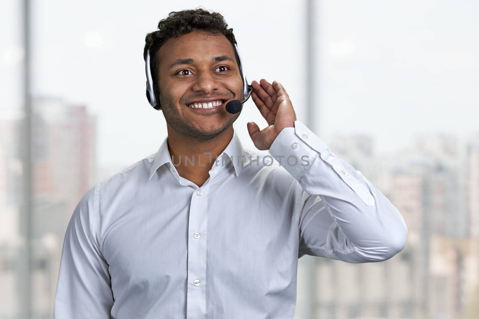 Young professional call center agent talking with someone. Blur office window in the background.