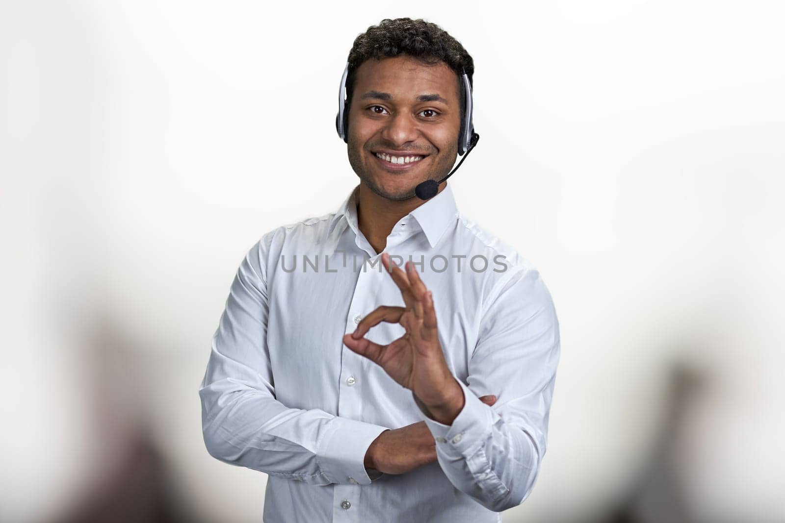 Smiling male call center agent showing okey symbol to camera. People, business and gestures concept.