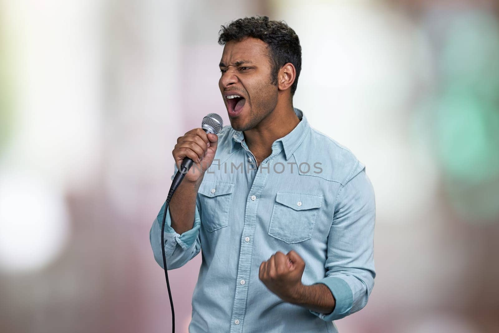 Passionate male singer performing favorite song. Abstract bokeh background. Handsome man singing with passion.