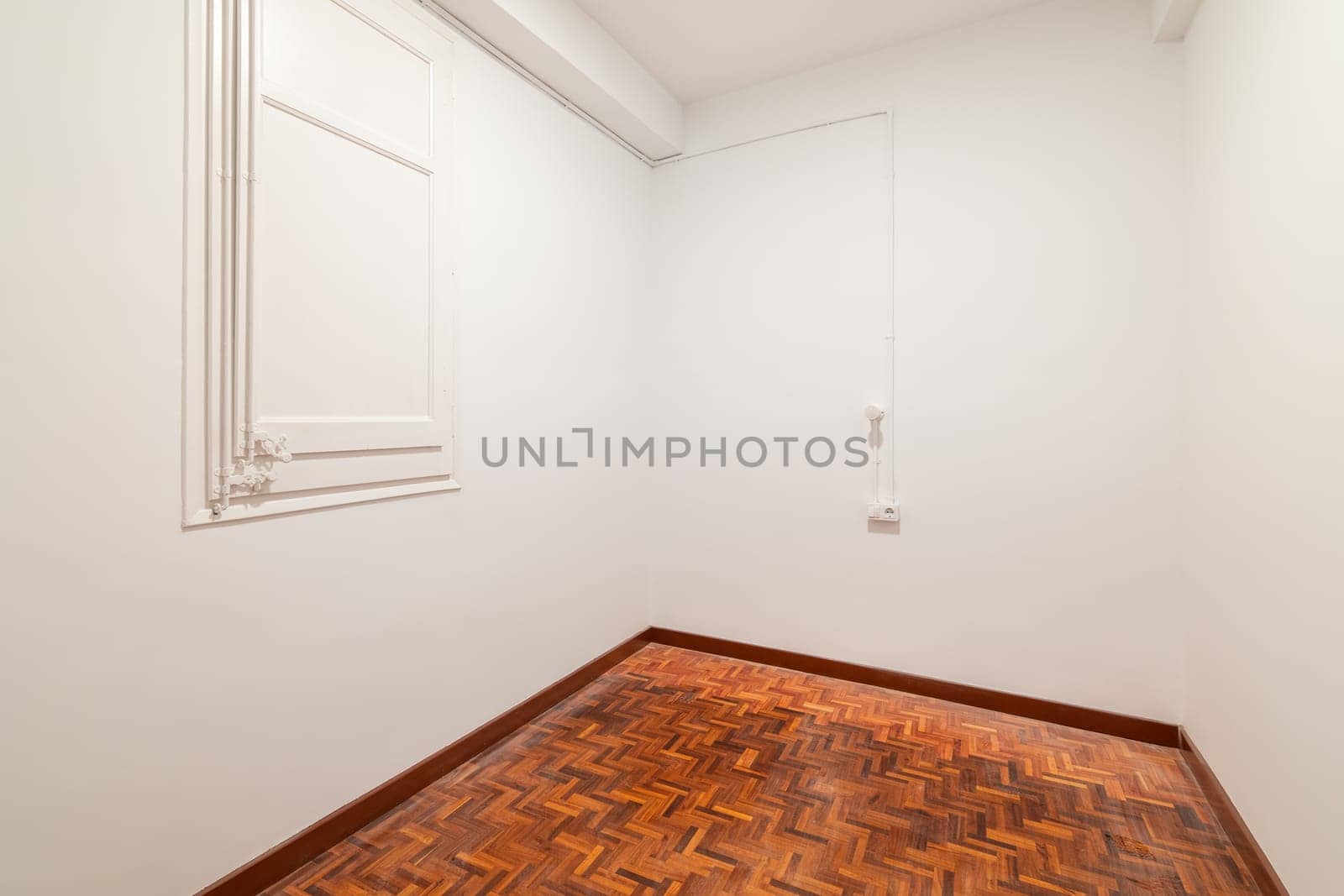 The empty room features a hardwood floor with wood stain and white painted walls, creating an artful space with a simple yet elegant aesthetic.