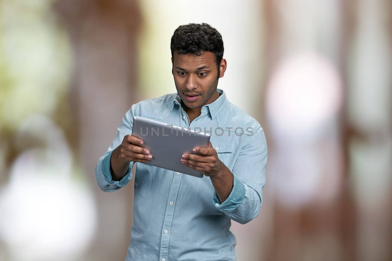 Young handsome man using digital tablet pc. Abstract bokeh background.
