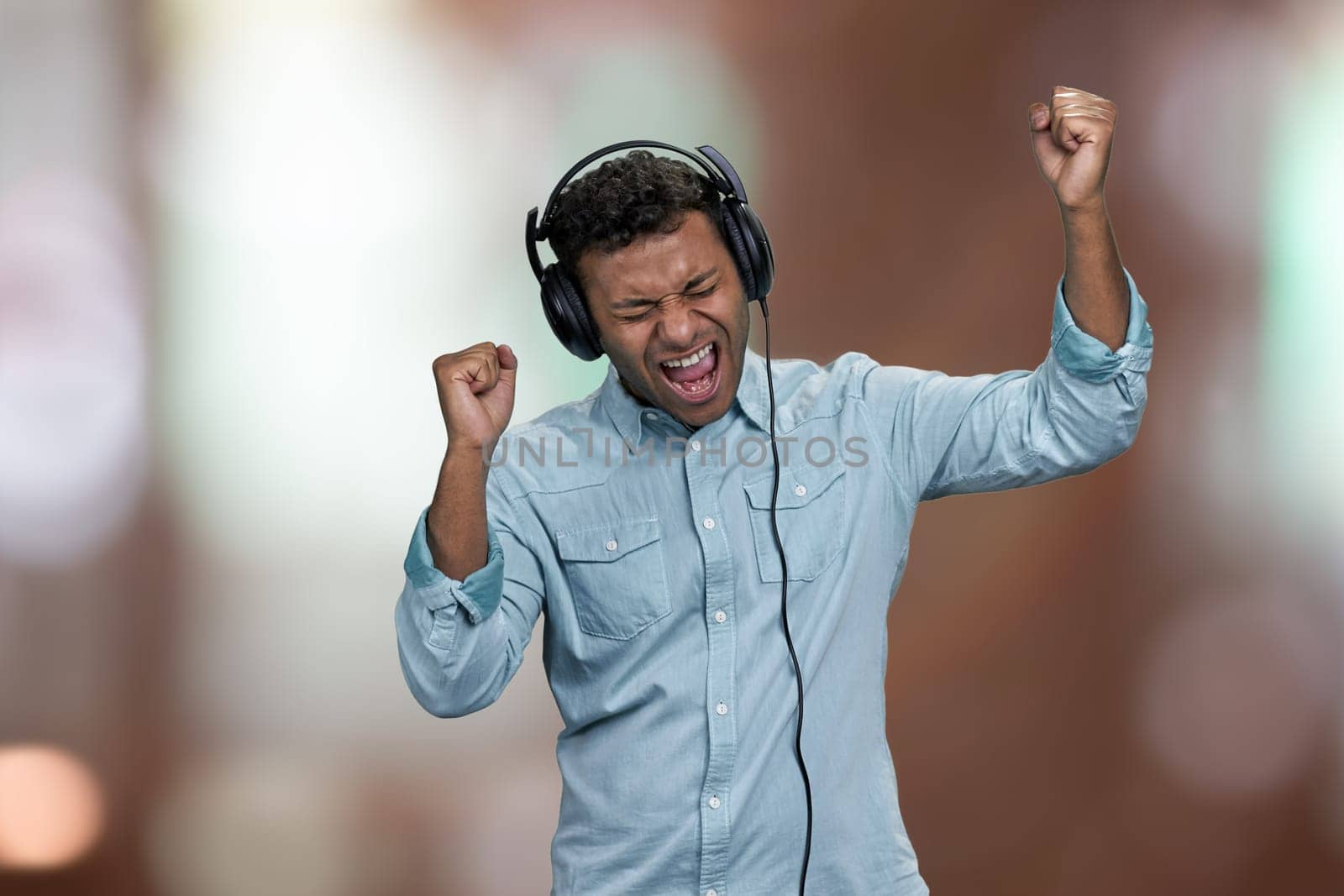 Man listening favorite song with headphones. Abstract bokeh background. People, music, emotions and fun concept.