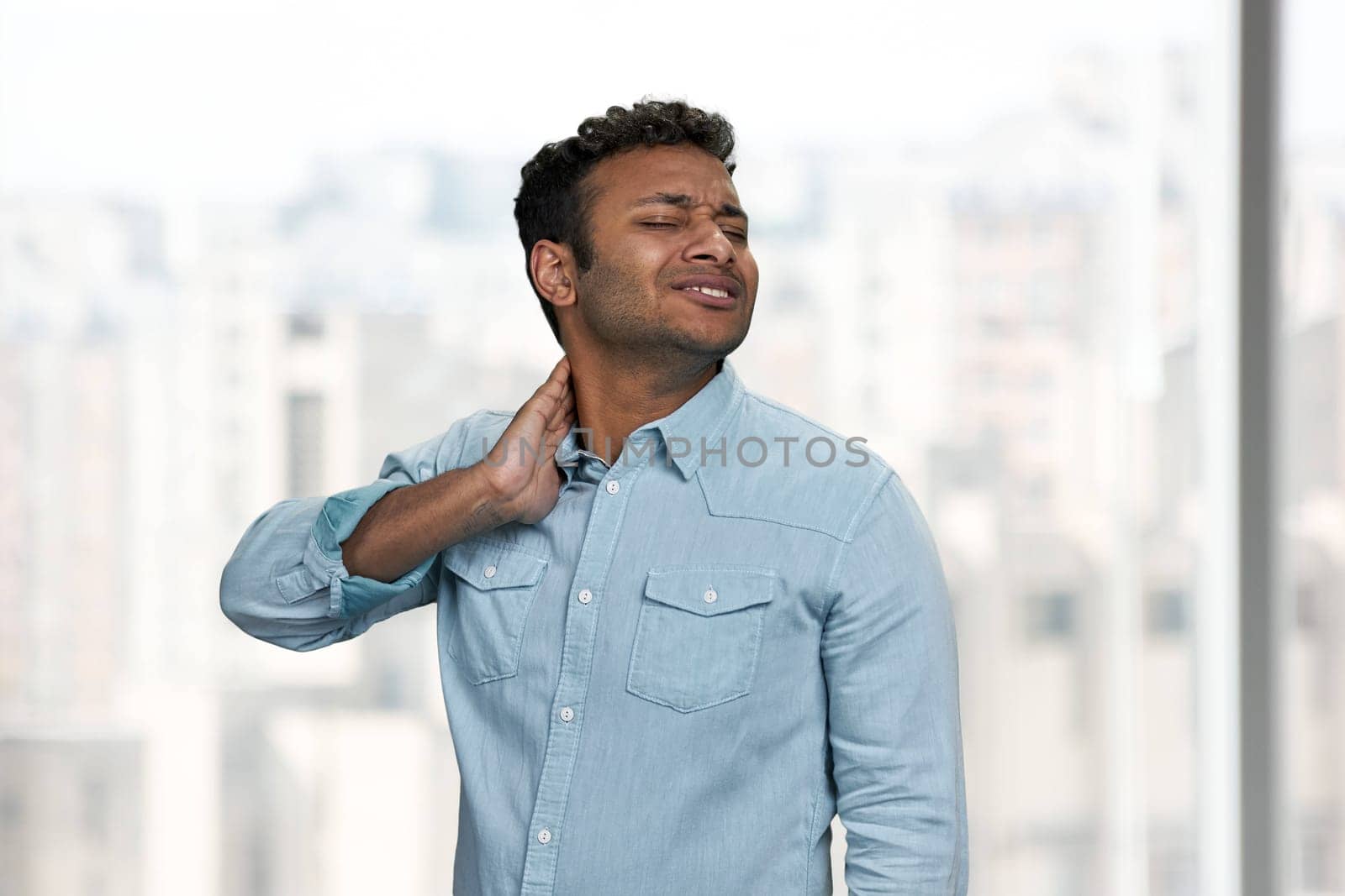 Stressed young man touching his nape. Pain concept. Health problem.