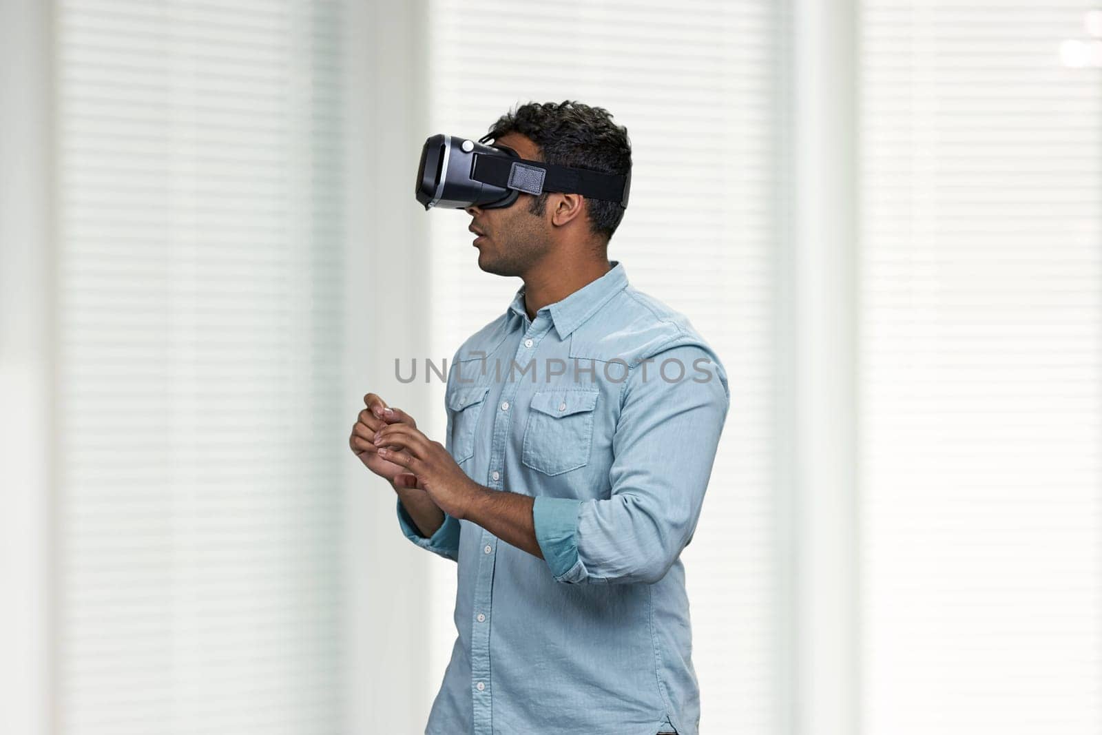 Indian man with VR goggles experiencing VR game. People, technology and fun concept.