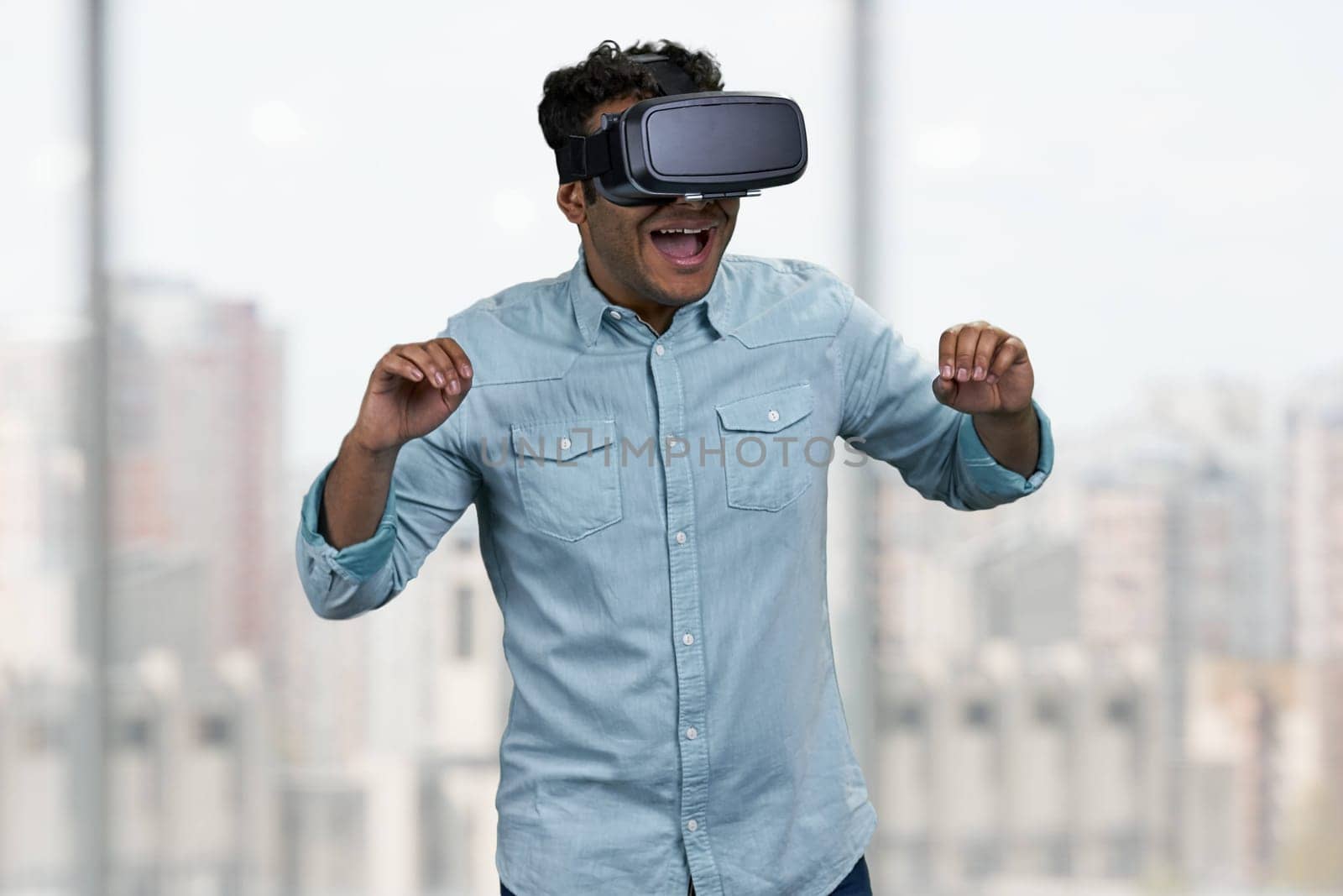 Young cheerful dark-skinned man using vr headset. People, modern technology and leisure concept.