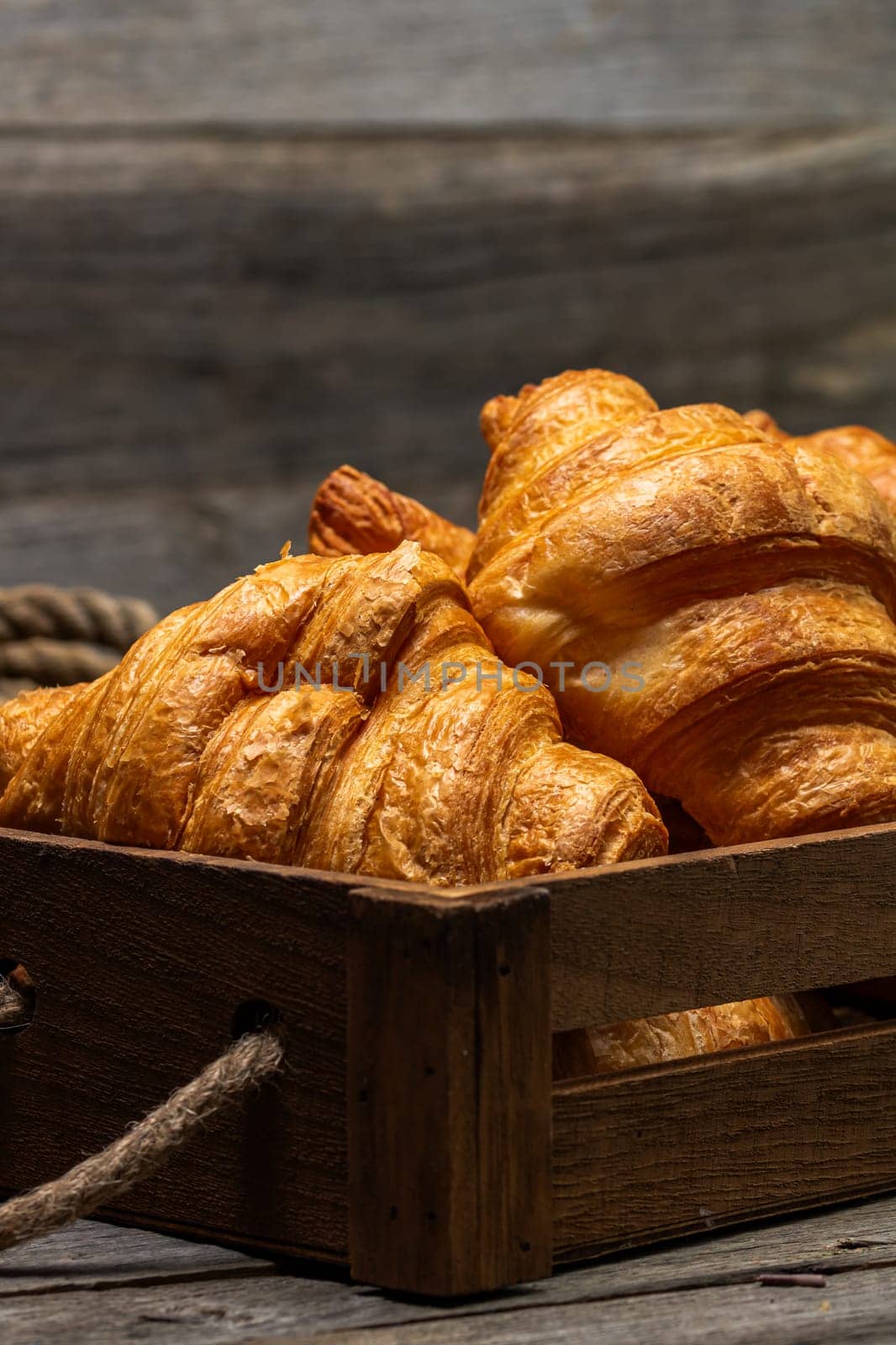 Wooden crate with delicious, fresh croissants isolated. French breakfast concept. by vladispas