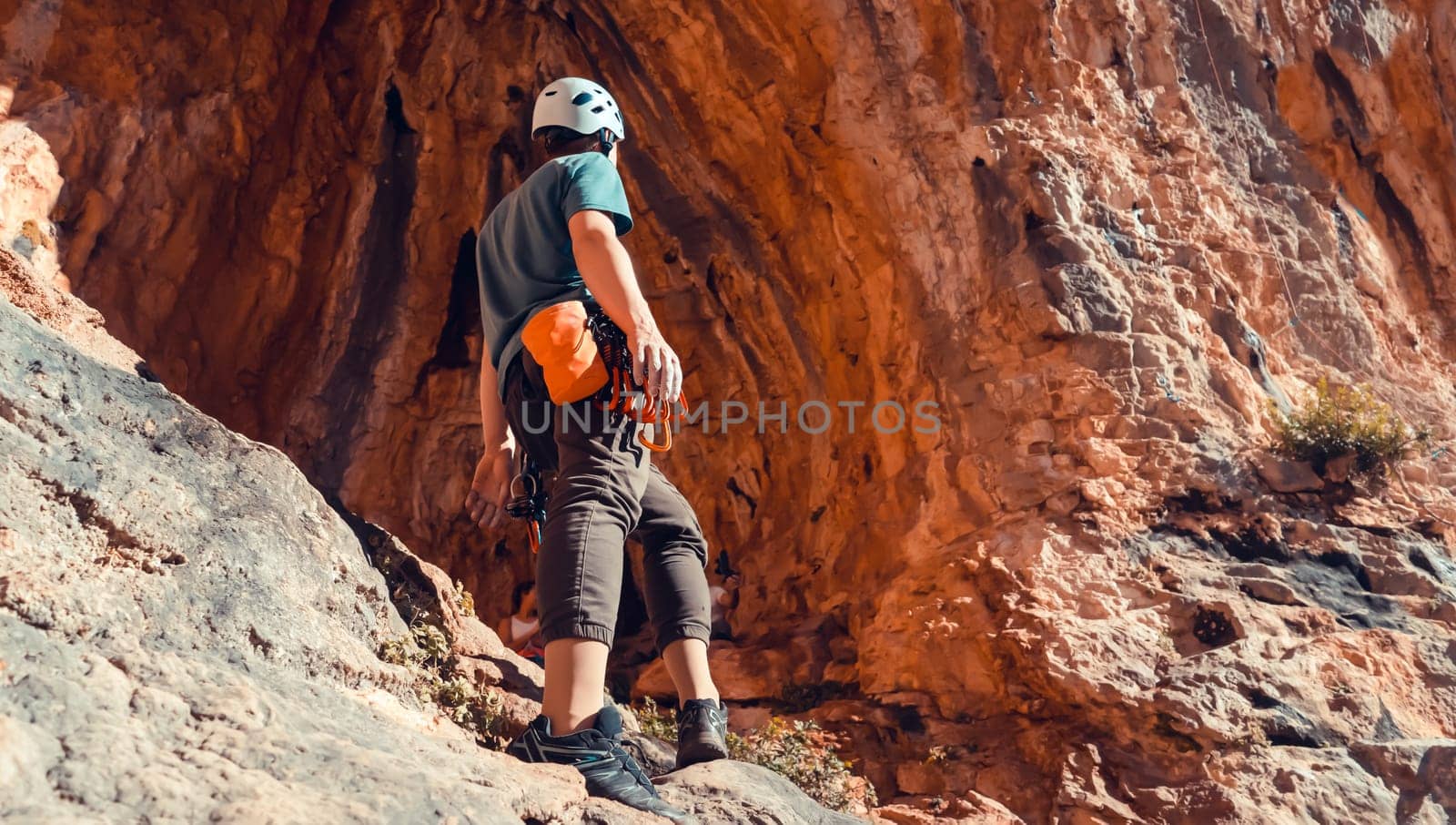 A man is engaged in rock climbing, stands against the background of a beautiful red cave before training, the climber leads an active lifestyle and is involved in extreme sports.
