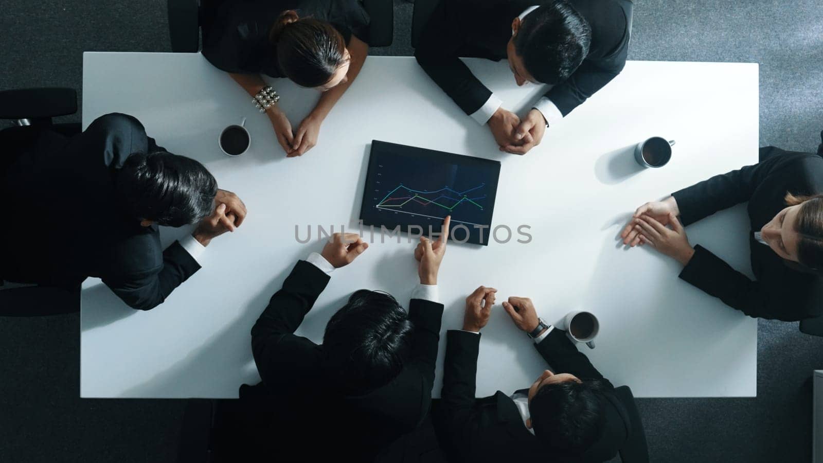 Top down aerial view of smart businessman looking at financial chart while hold tablet display stock market statistic and explain marketing idea to diverse investors. Creative business. Directorate.