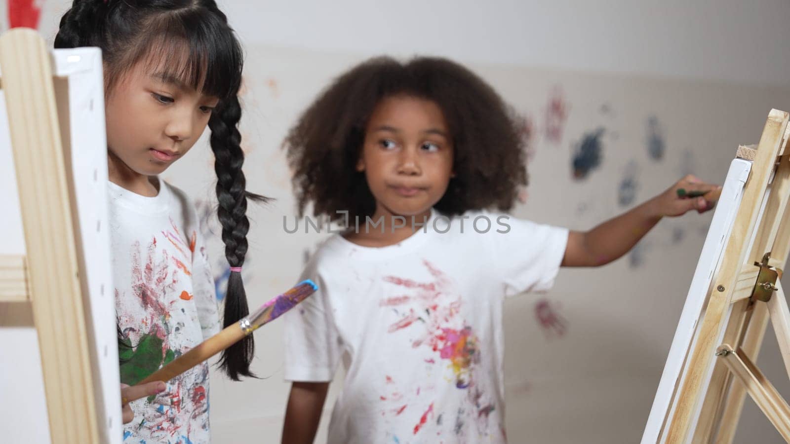 Happy creative african girl painted or draw canvas together with asian boy. Group of playful student create funny painting or artwork painted by watercolor. Creativity activity concept. Erudition.