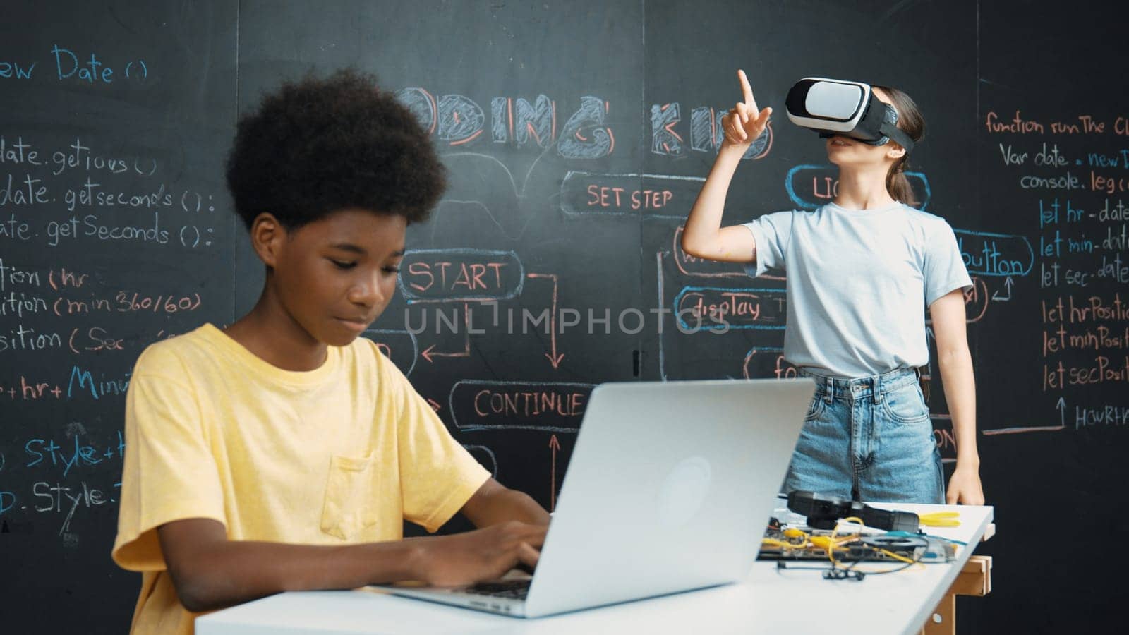 Smart african student programing and coding innovative system while caucasian girl enter in metaverse or virtual world by using VR or head set at blackboard in STEM technology classroom. Edification.