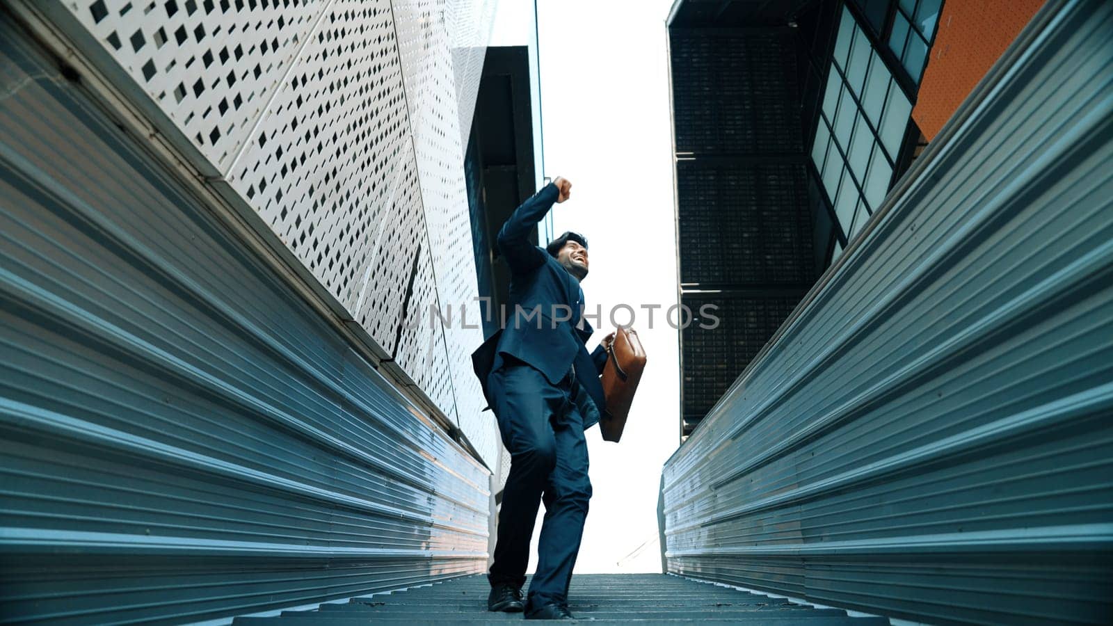 Low angle view of young smiling business man dance between building. Exultant. by biancoblue