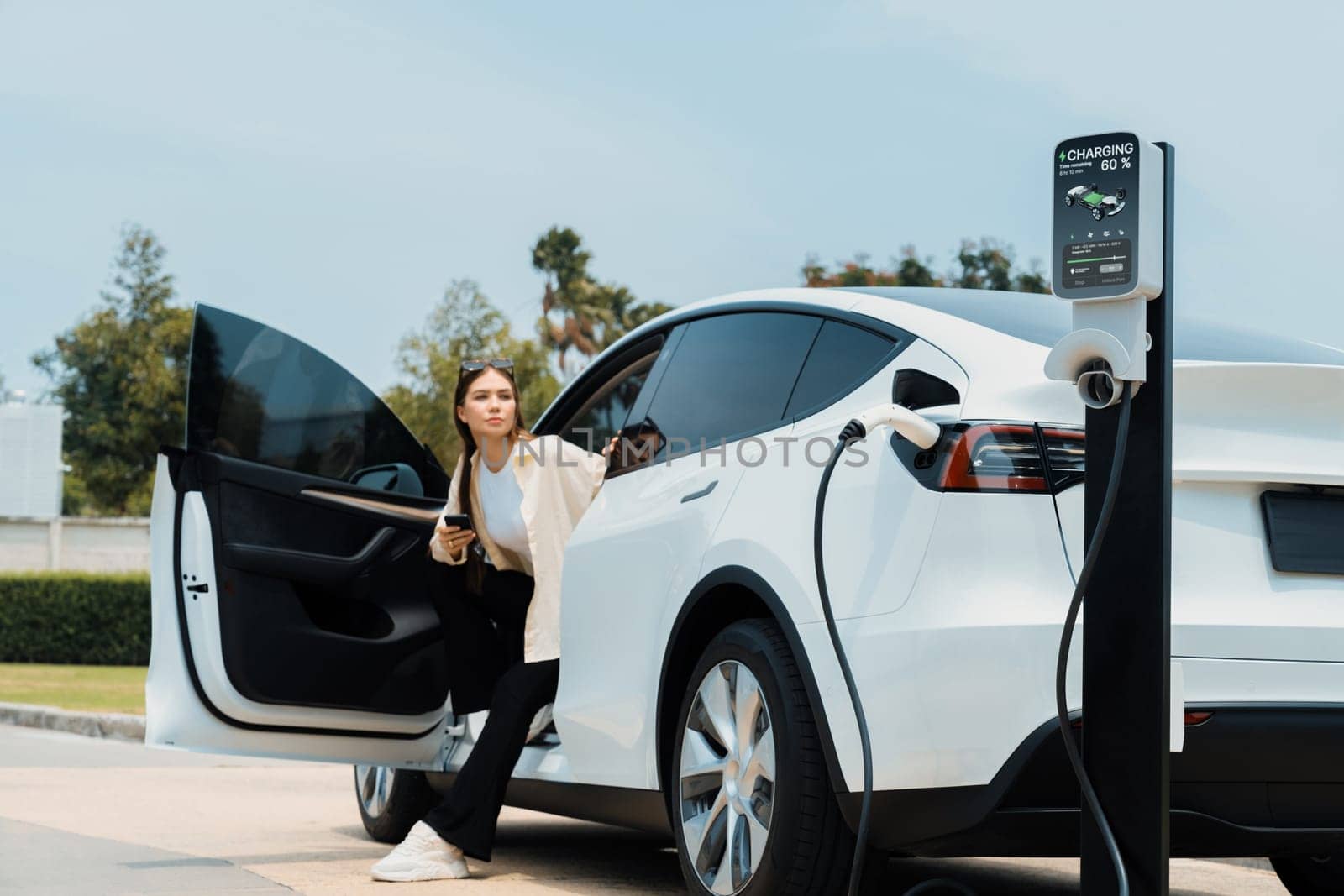Young woman use smartphone to pay for electricity for EV car. Expedient by biancoblue