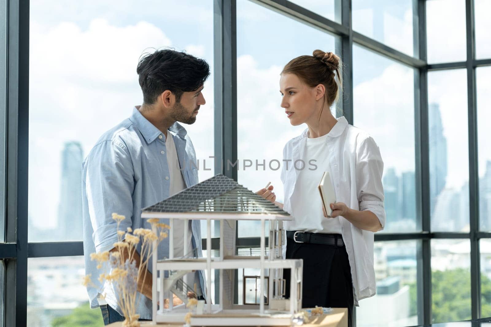 Professional architect engineer team discussing about house construction. Expert businesspeople sharing and brainstorming idea about house design. Working together. Skyscraper. Tracery.