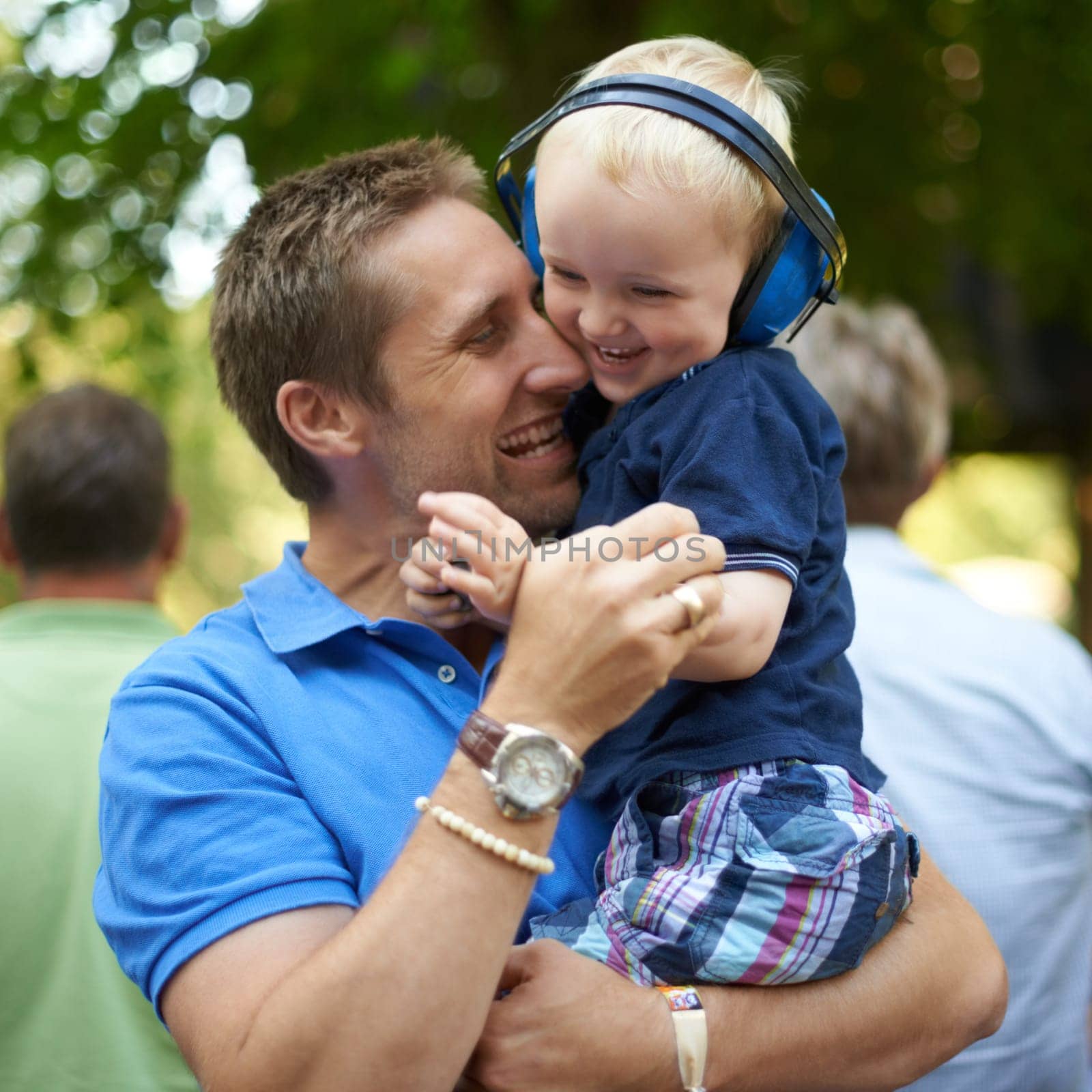 Father, hug and baby at outdoor festival for family together, happiness and headphones for loud sound. Man, kid and love for child, playful and laugh at music concert in Hollywood for summer holiday.