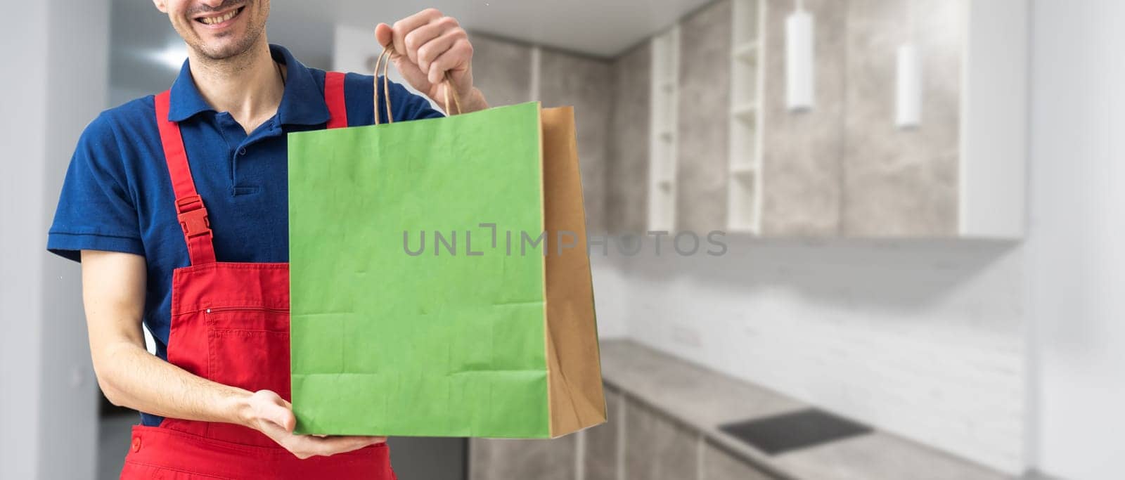 Young handsome delivery man holding paper bag with takeaway food happy with big smile. by Andelov13