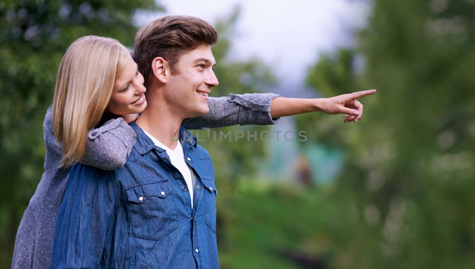 Couple, smile and happiness with pointing finger in park, outdoor setting and bonding with activities. Relationship, goals and romance with fun day in forest for lifestyle, wellness and relax by YuriArcurs