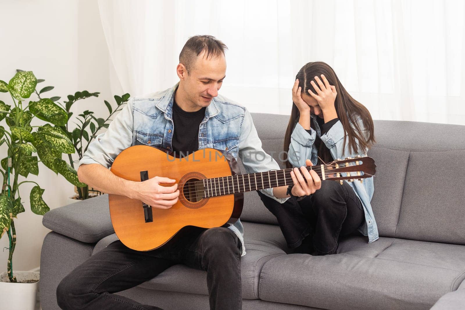 Little daughter and her father playing guitar at home. High quality photo