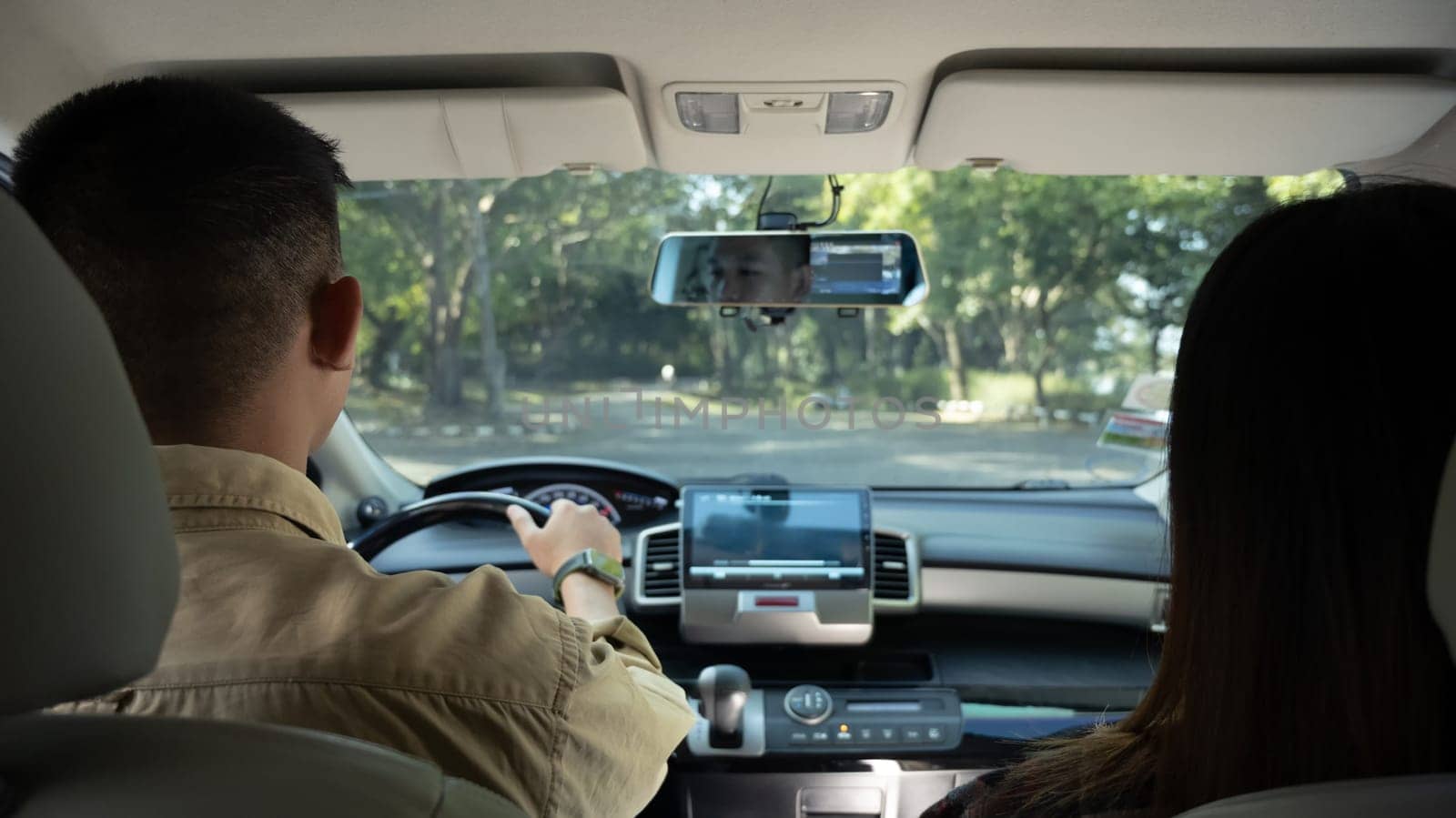 Back view of beautiful young couple driving comfortable automobile on a country road. Travel and vacation concept.