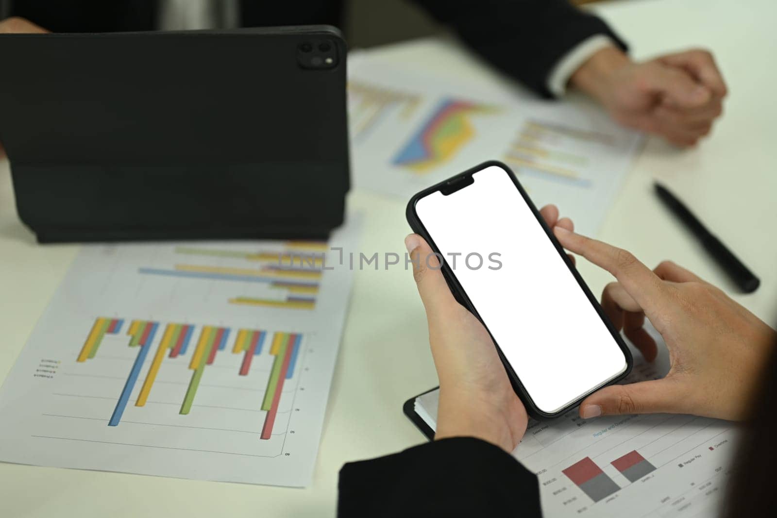 Cropped shot businesswoman using mobile phone while working with colleague at office.