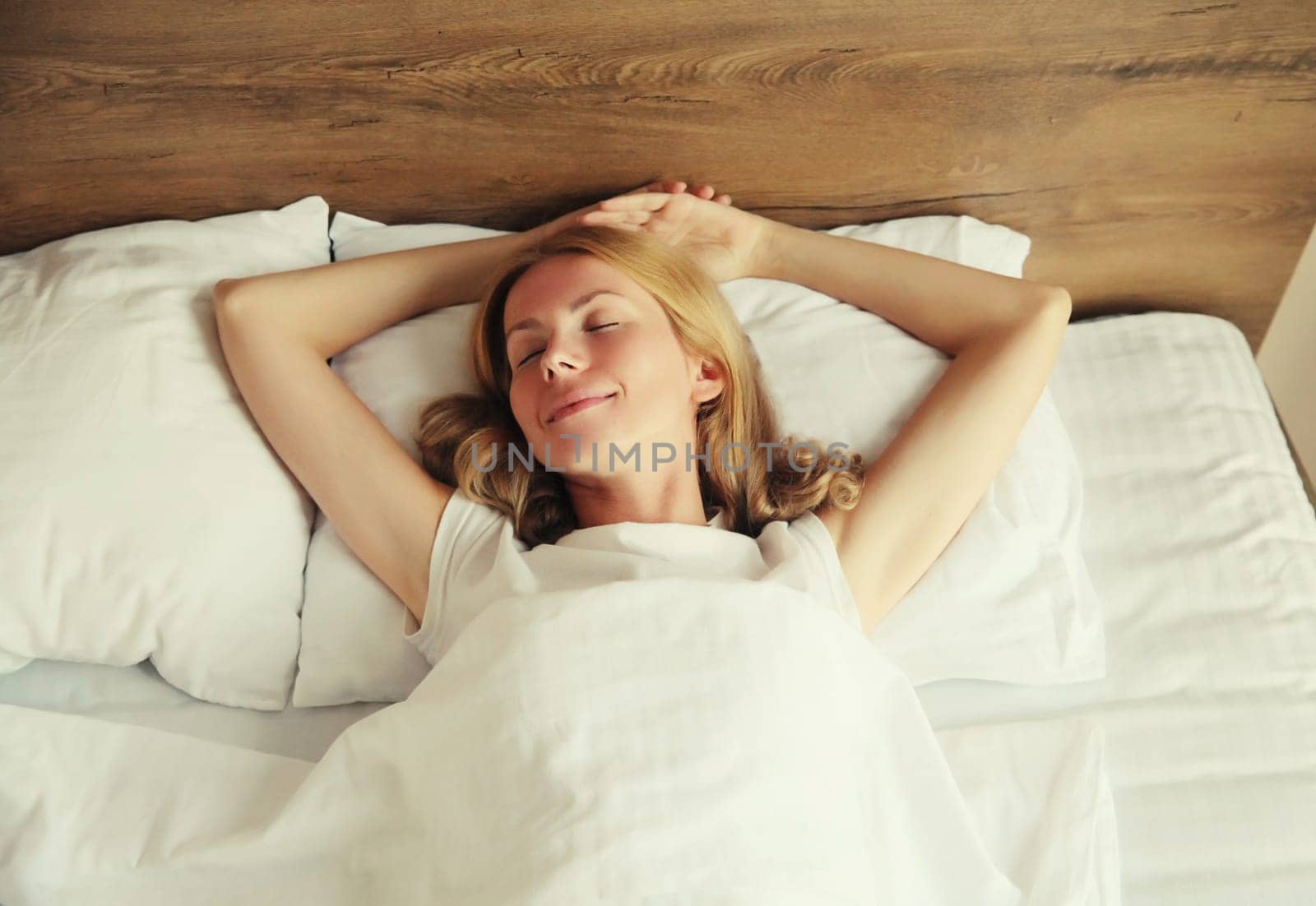 Young woman sleeping lying in bed on white soft comfortable pillow in bedroom at home