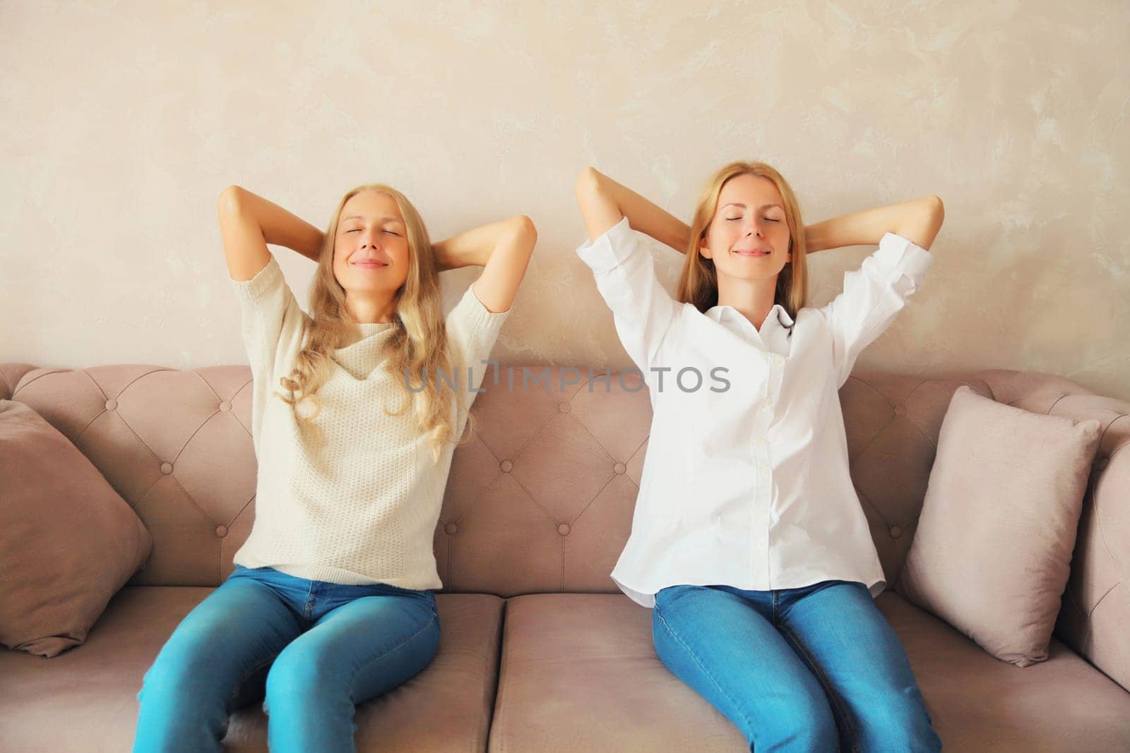 Relaxed happy caucasian middle aged mother and adult daughter resting together, women sitting on couch at home